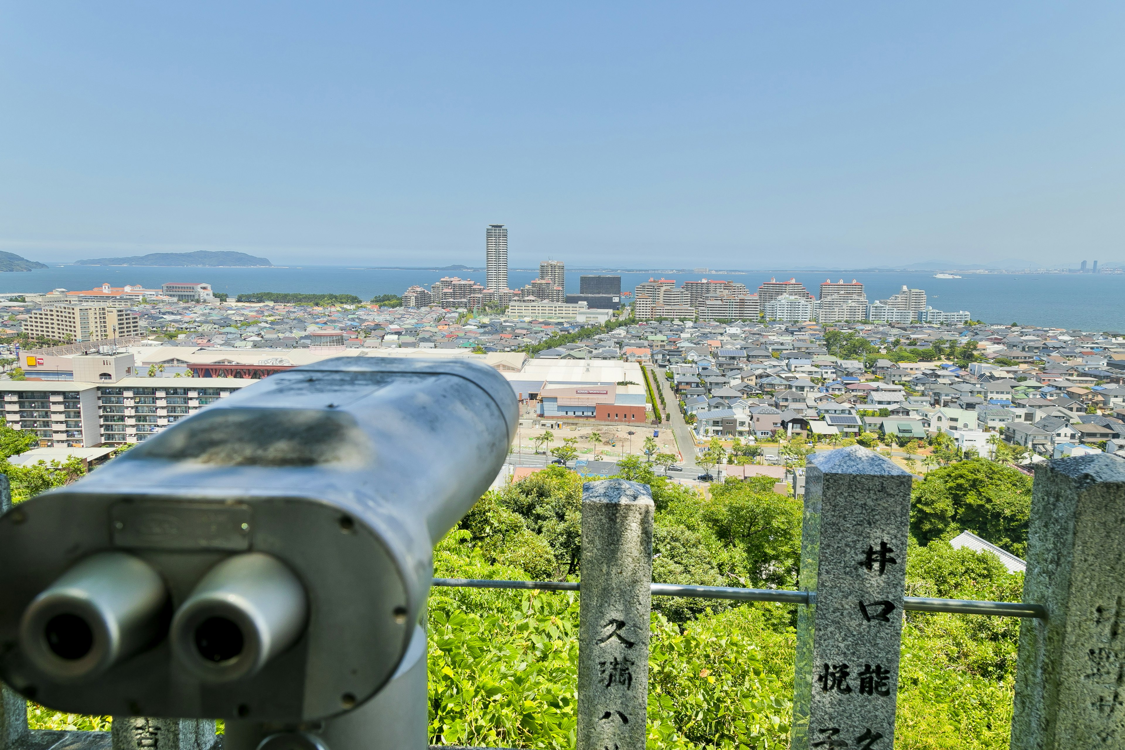 Panoramablick auf das Meer und die Stadt von einem Aussichtspunkt mit Fernglas