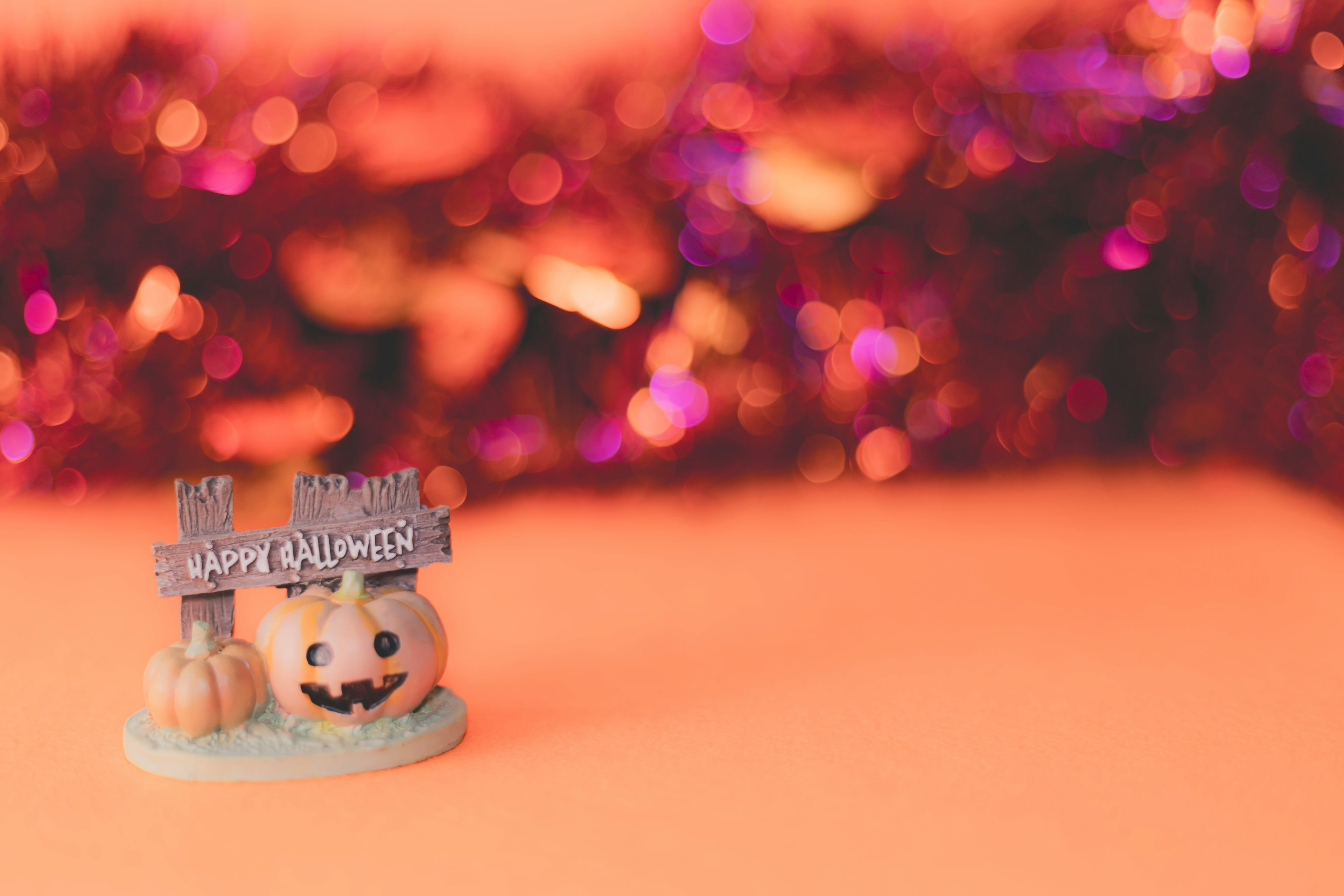 Pequeña figura de calabaza con un letrero de Halloween sobre un fondo naranja