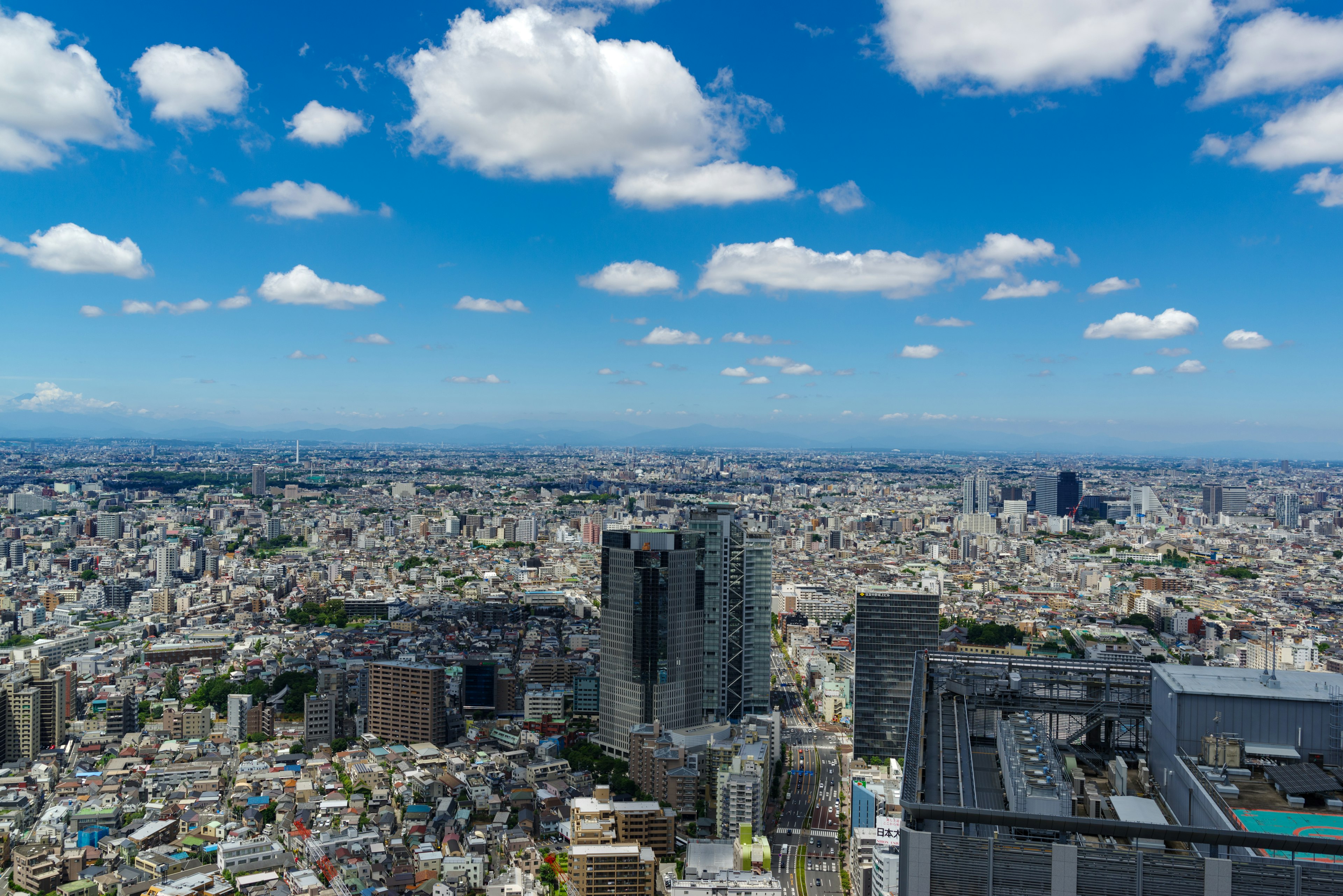 Pemandangan panorama Tokyo dengan gedung pencakar langit dan lanskap kota yang luas di bawah langit biru dengan awan