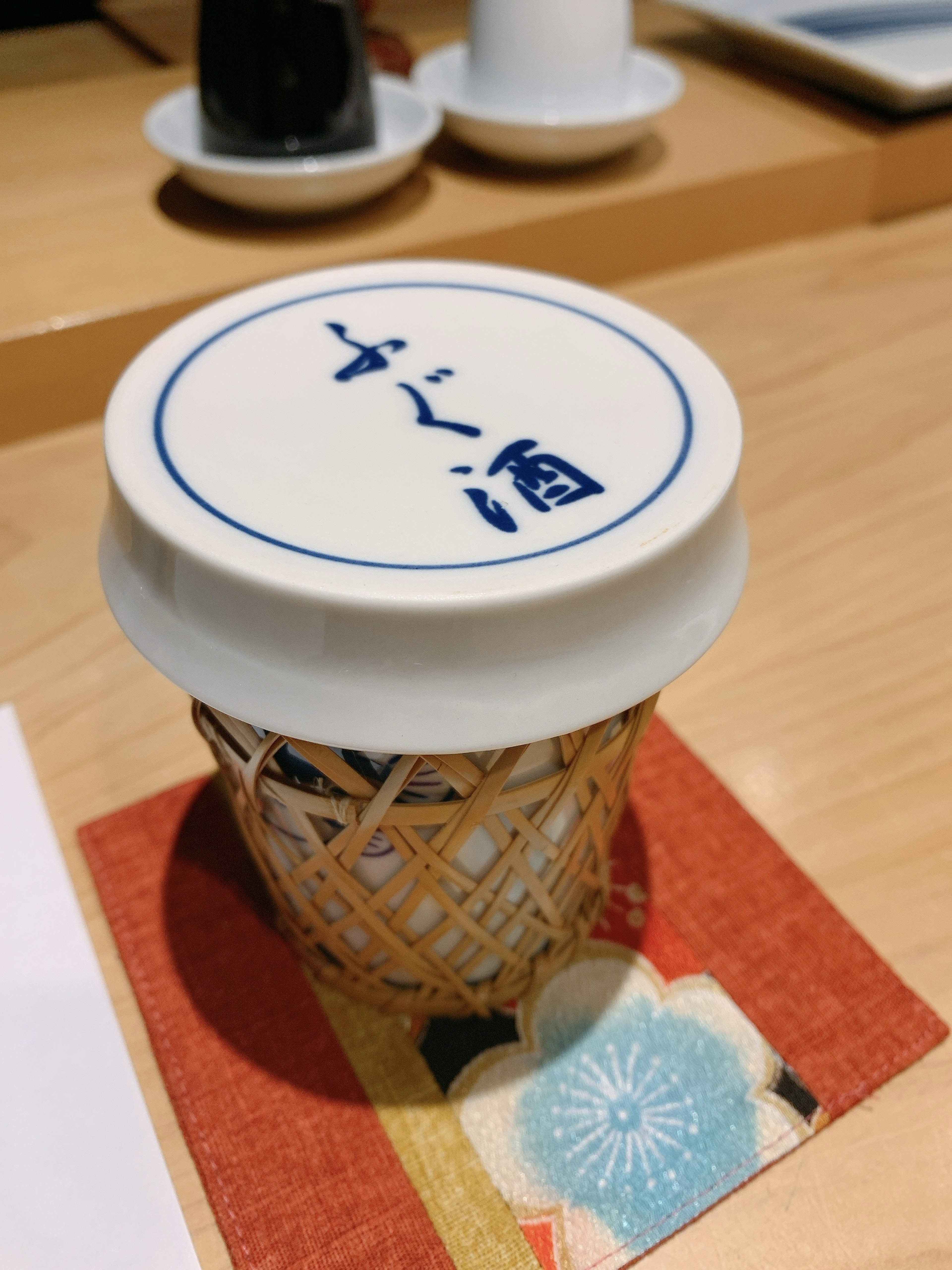 Récipient de saké japonais dans une tasse en bois avec un sous-verre décoratif