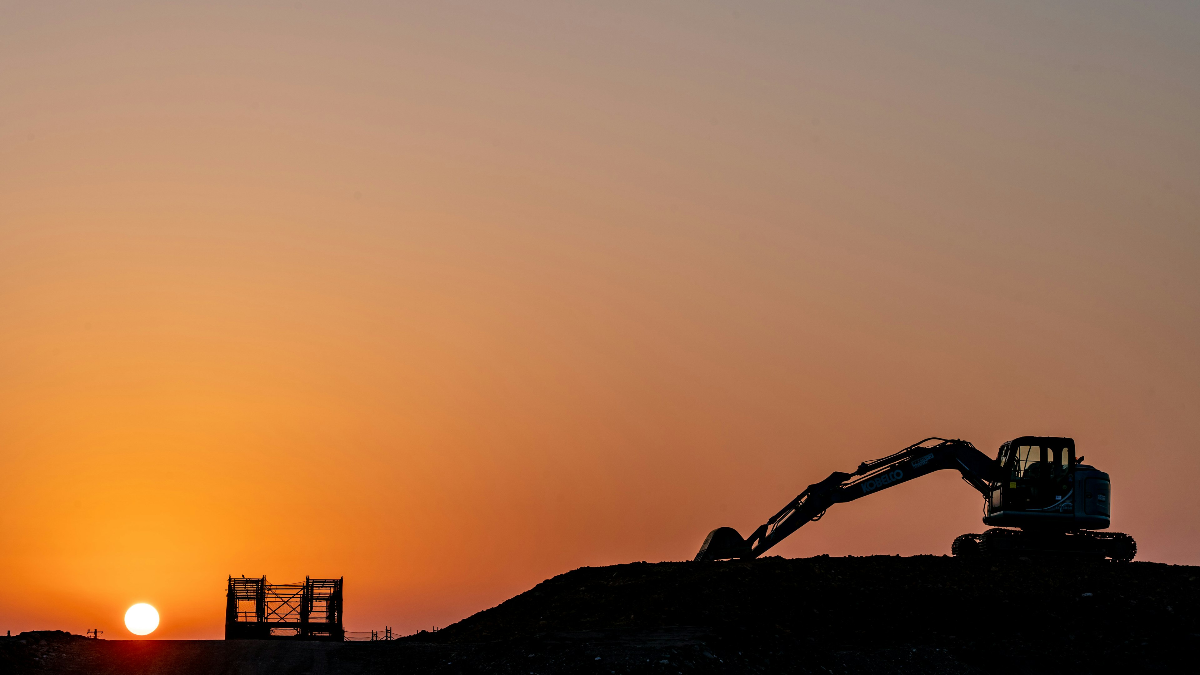 Silhouette of construction machinery against the sunset