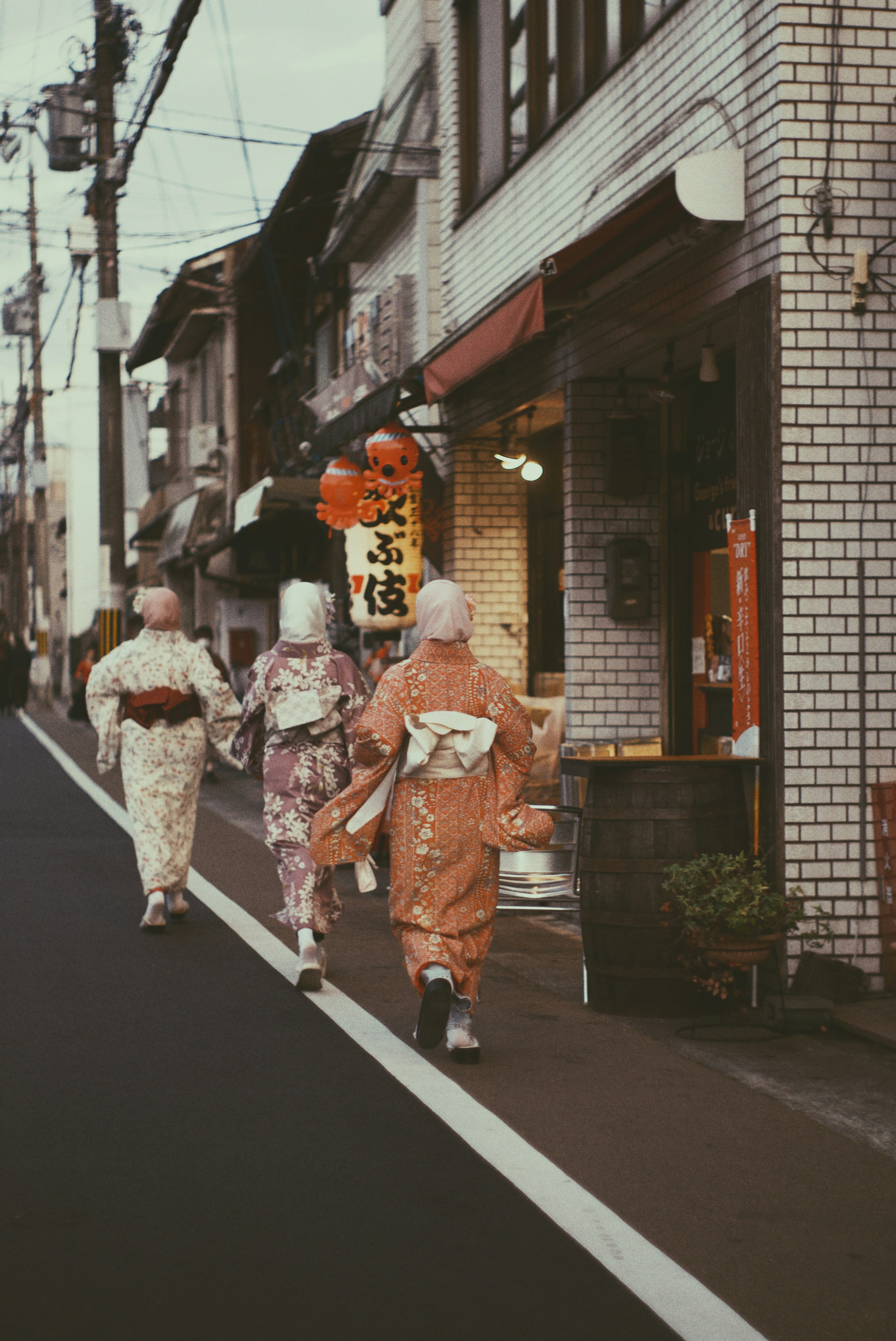 Wanita berpakaian kimono berjalan di sepanjang jalan