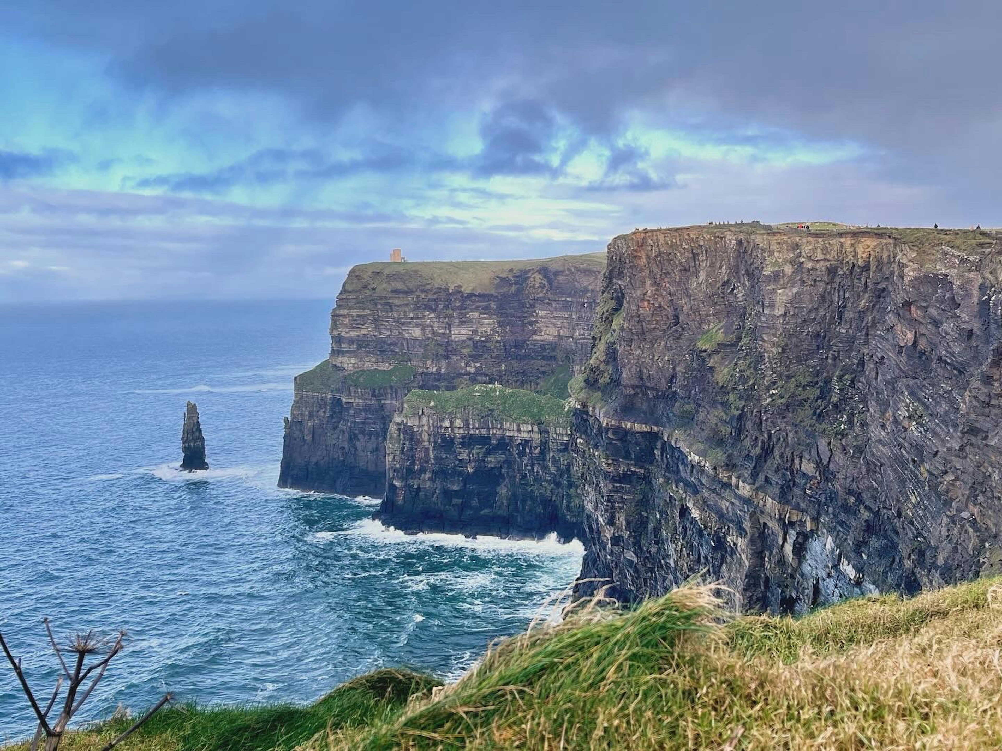 Falaises impressionnantes avec un rocher émergeant de l'océan sous un ciel bleu