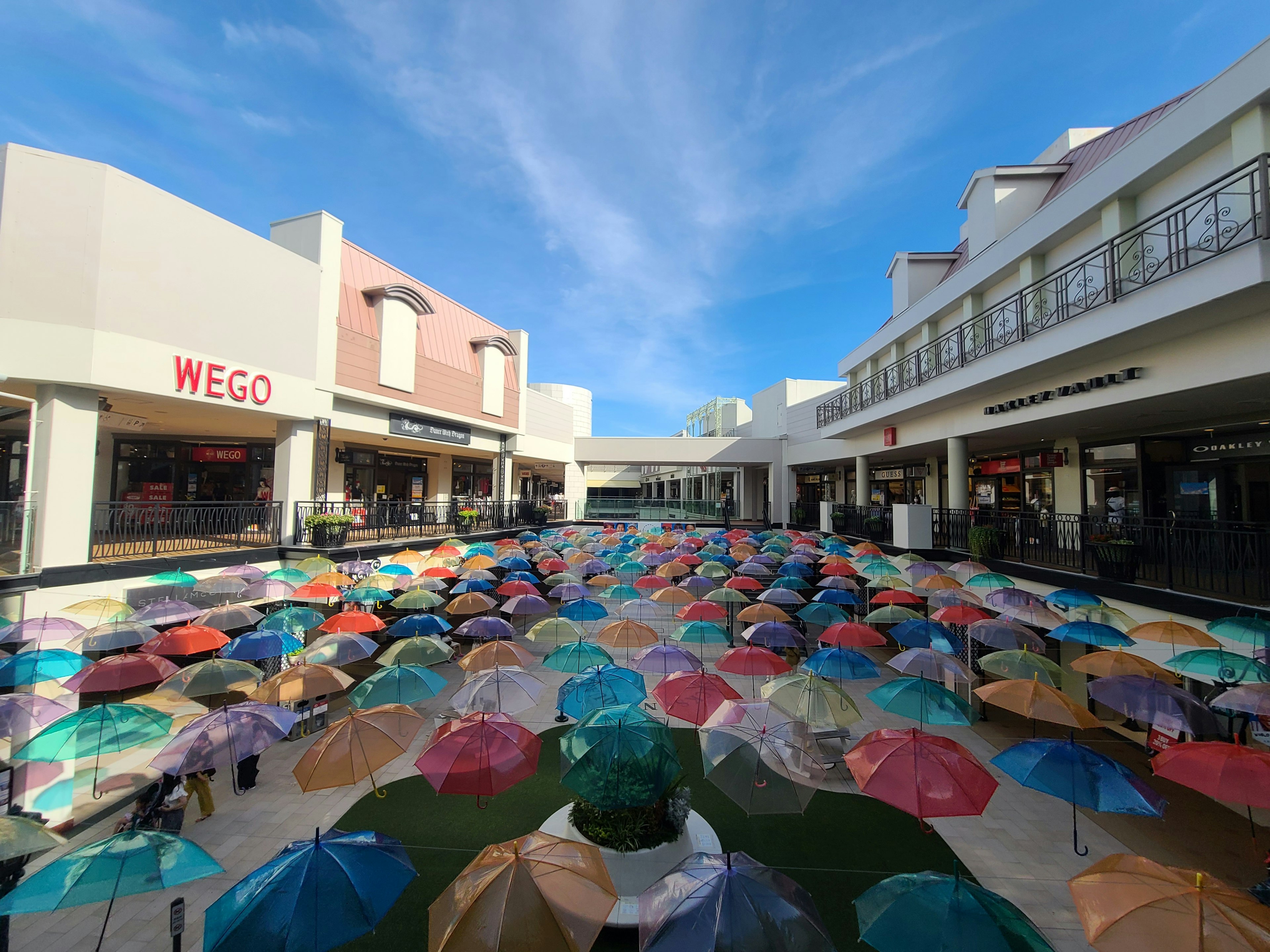 Parapluies colorés disposés sous un ciel bleu dans la cour d'un centre commercial