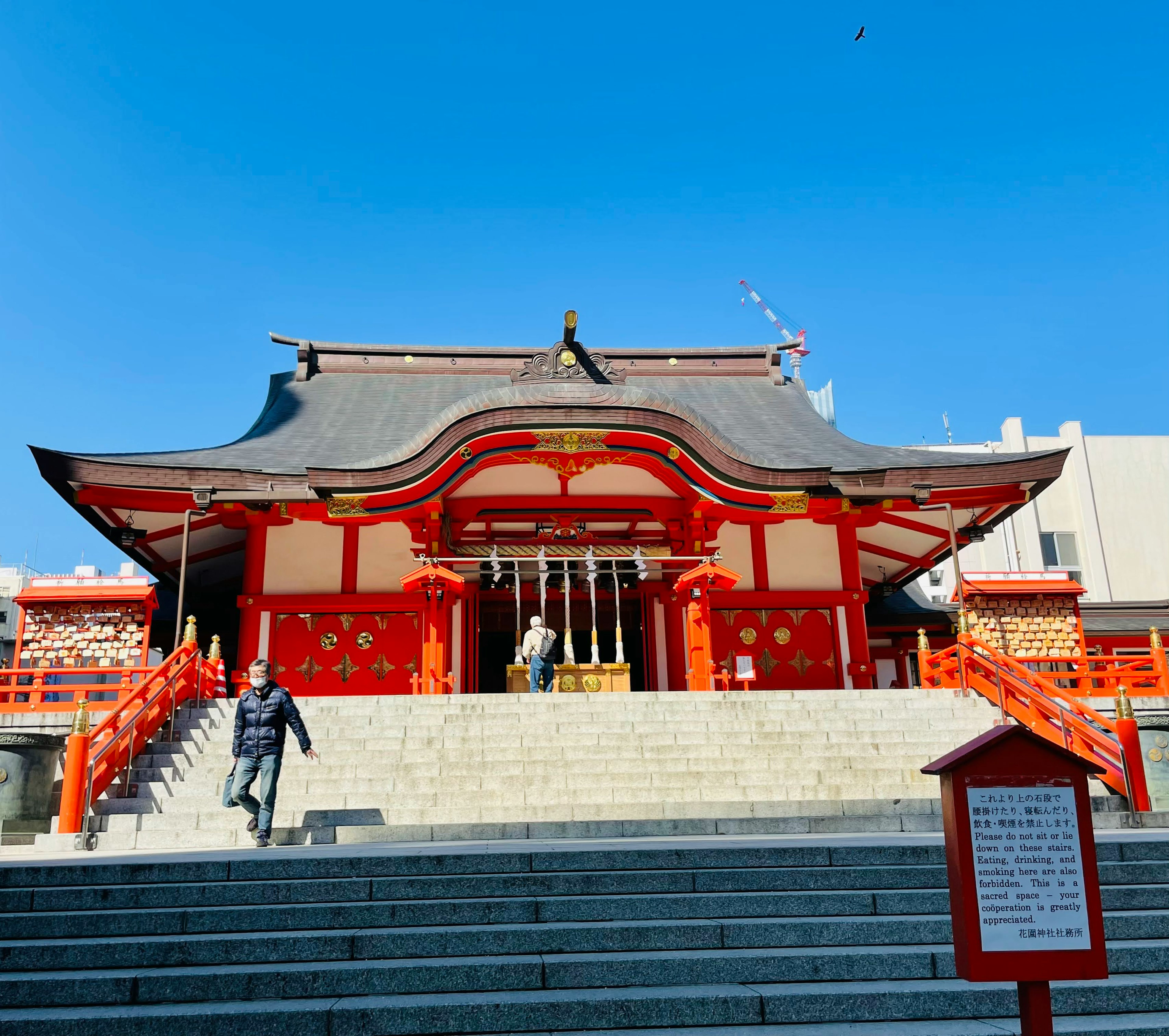 一个鲜艳的红色神社建筑，带有阶梯和清澈的蓝天