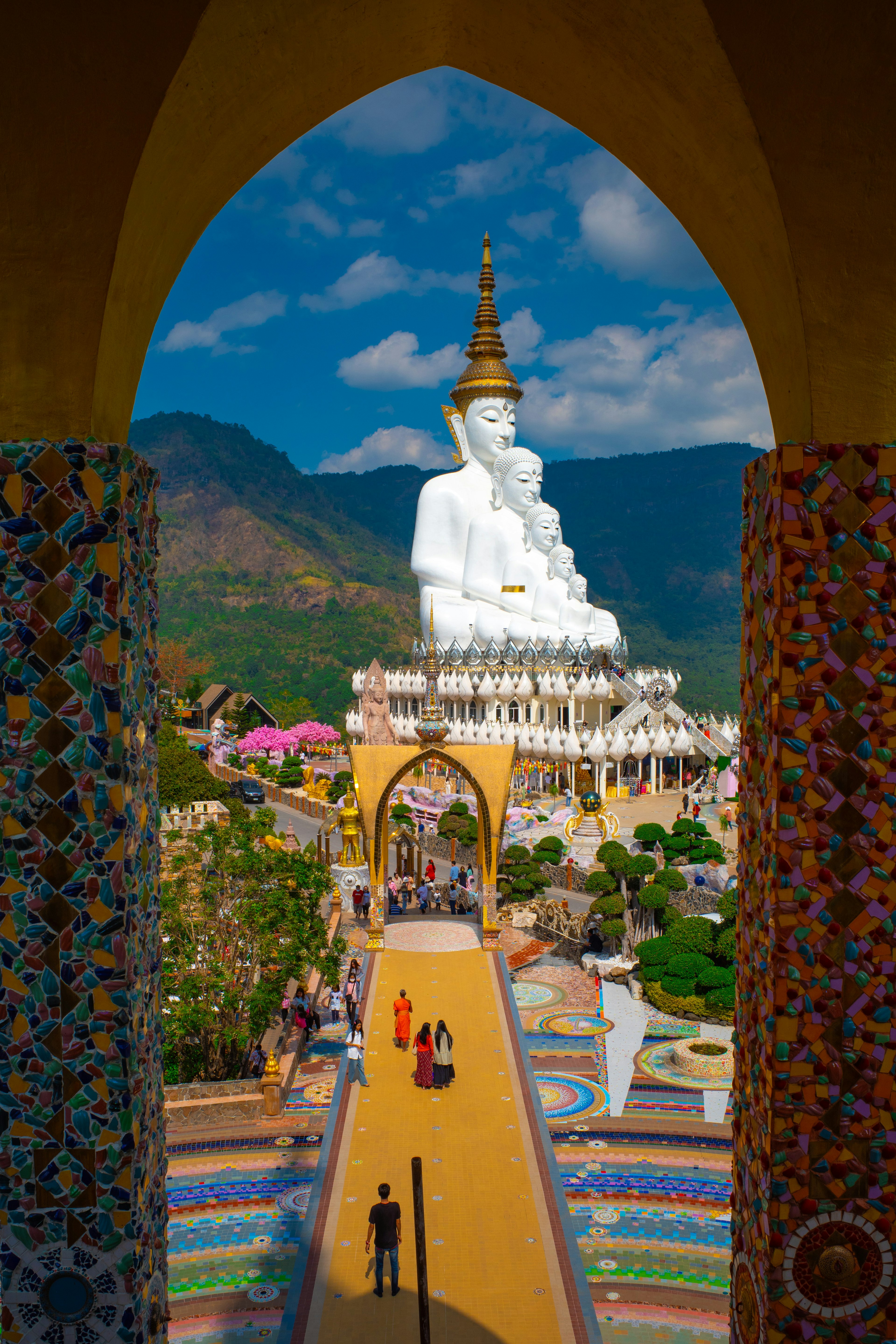 View of a white Buddha statue surrounded by colorful mosaics and a vibrant temple