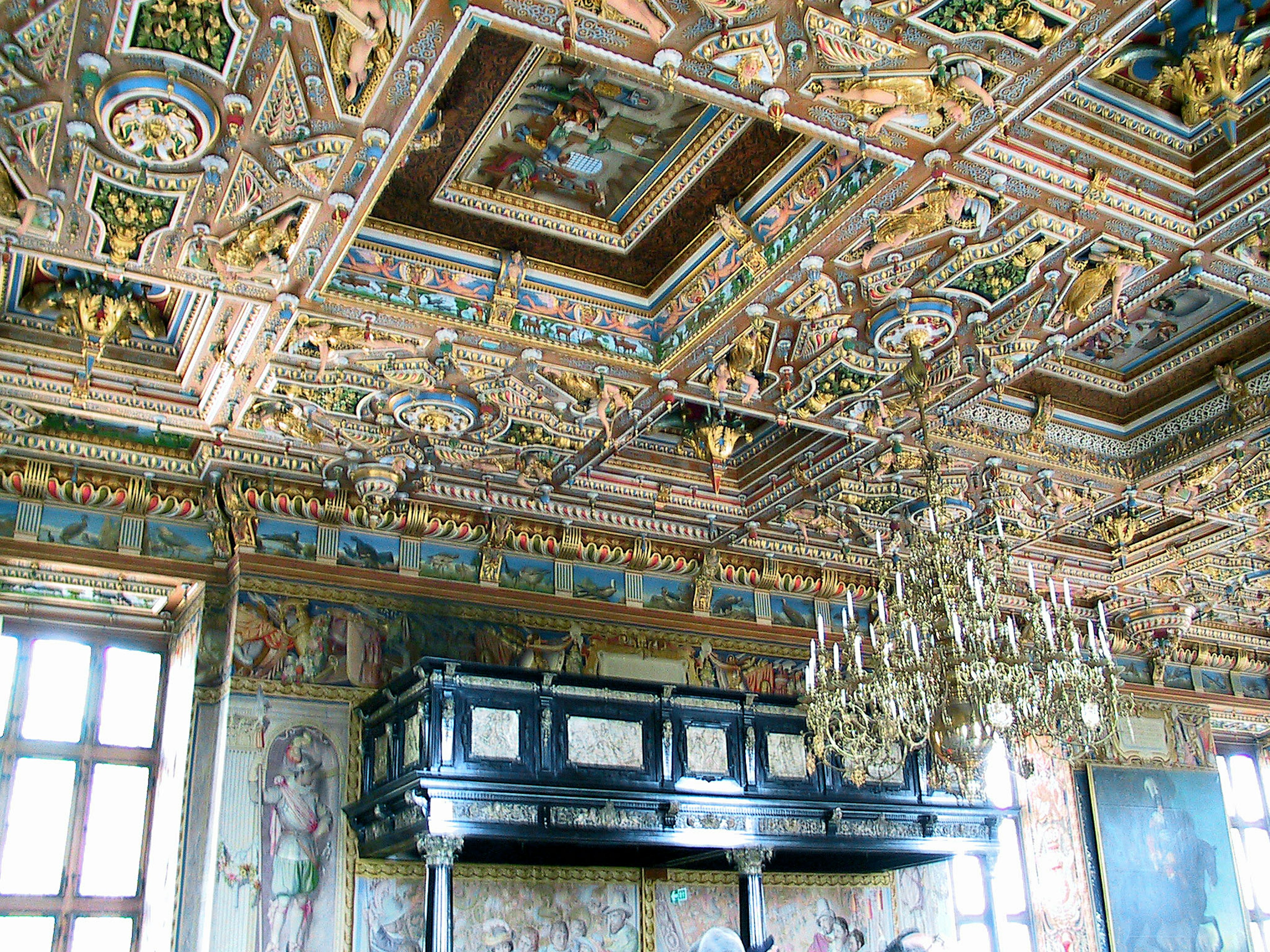 Room with a lavishly decorated ceiling and chandelier