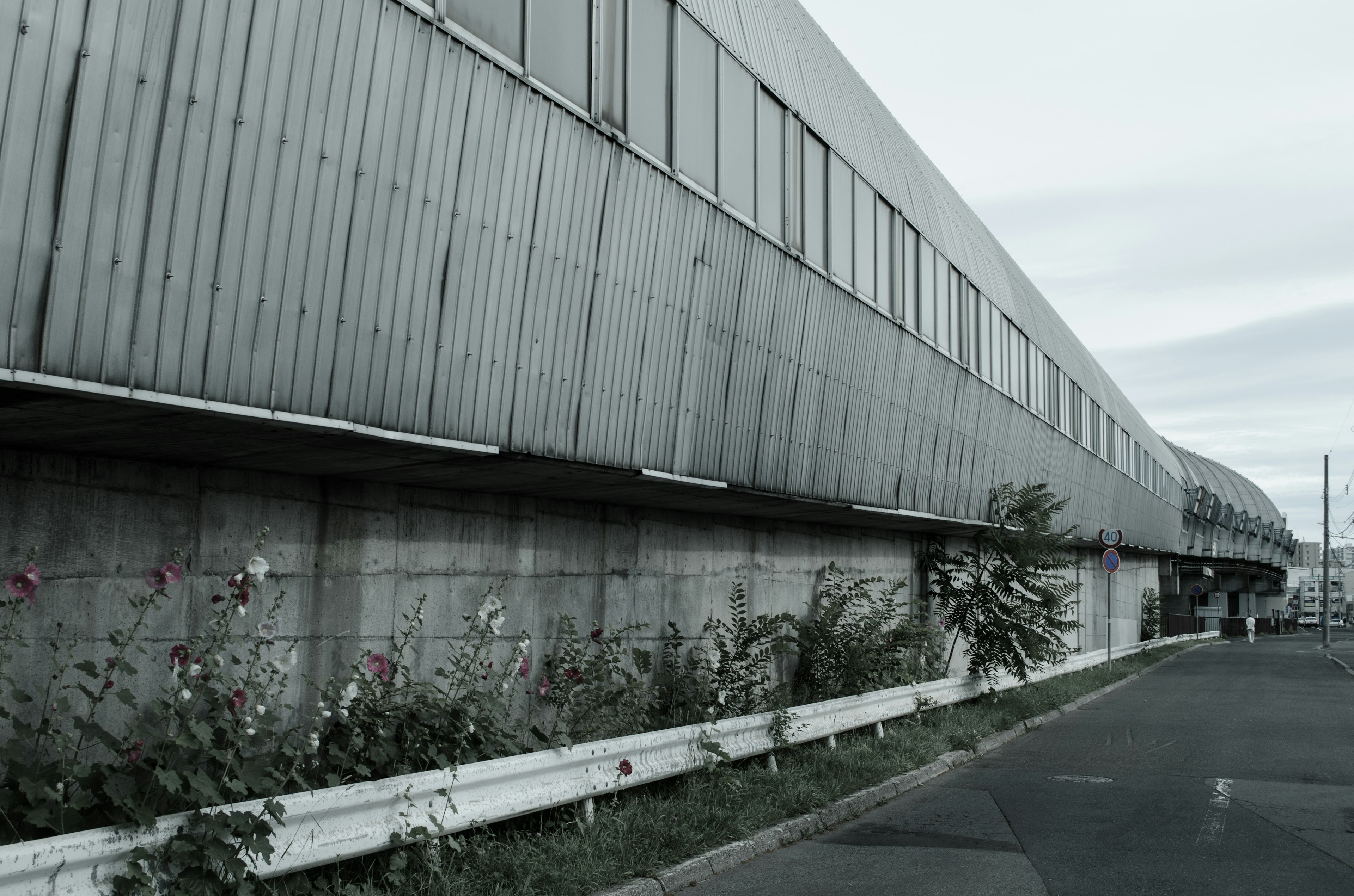 Côté d'un bâtiment industriel avec une clôture blanche et des plantes