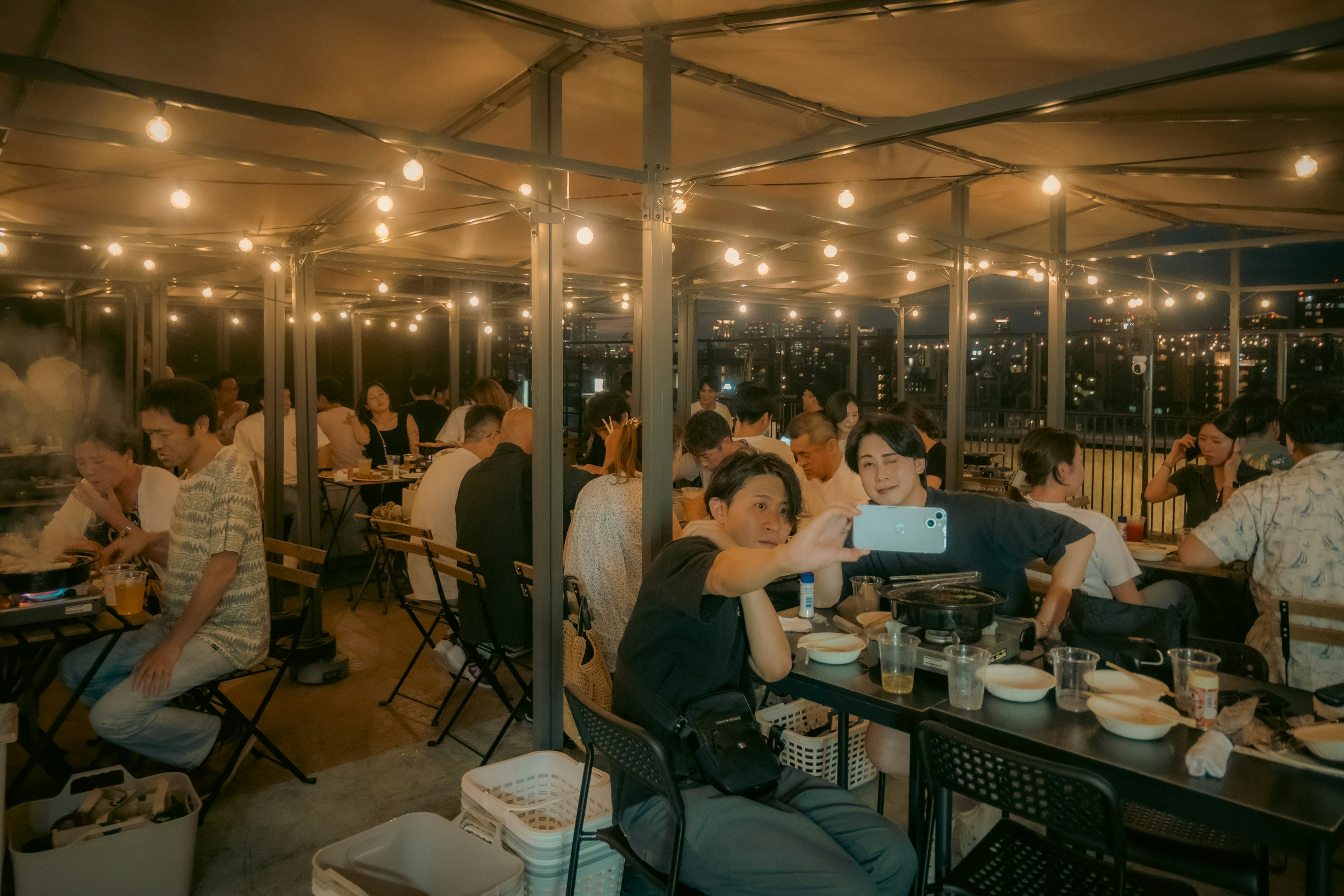 Menschen genießen das Abendessen in einem Außenrestaurant mit warmem Licht