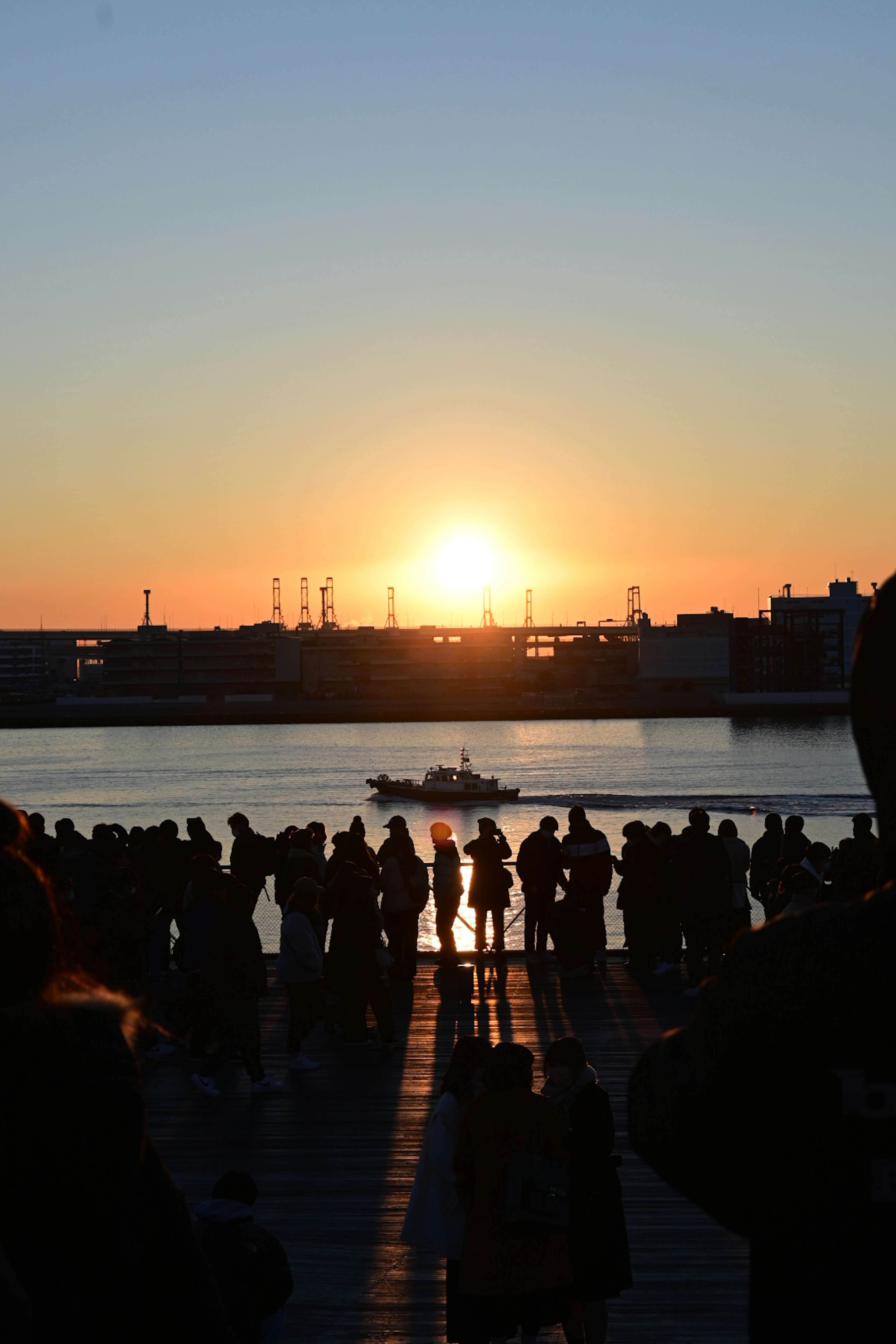 夕日が沈む川の前に立つ人々のシルエット