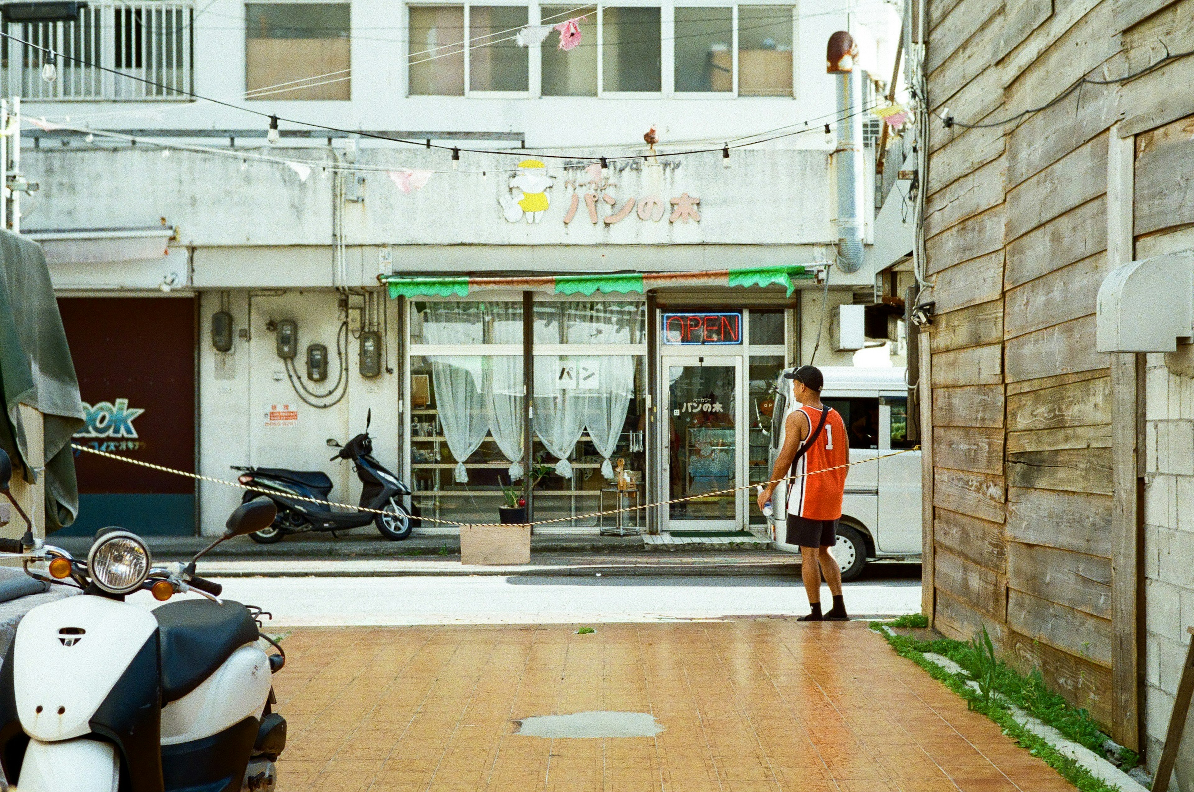 オレンジのシャツを着た男性が店の前に立っている風景