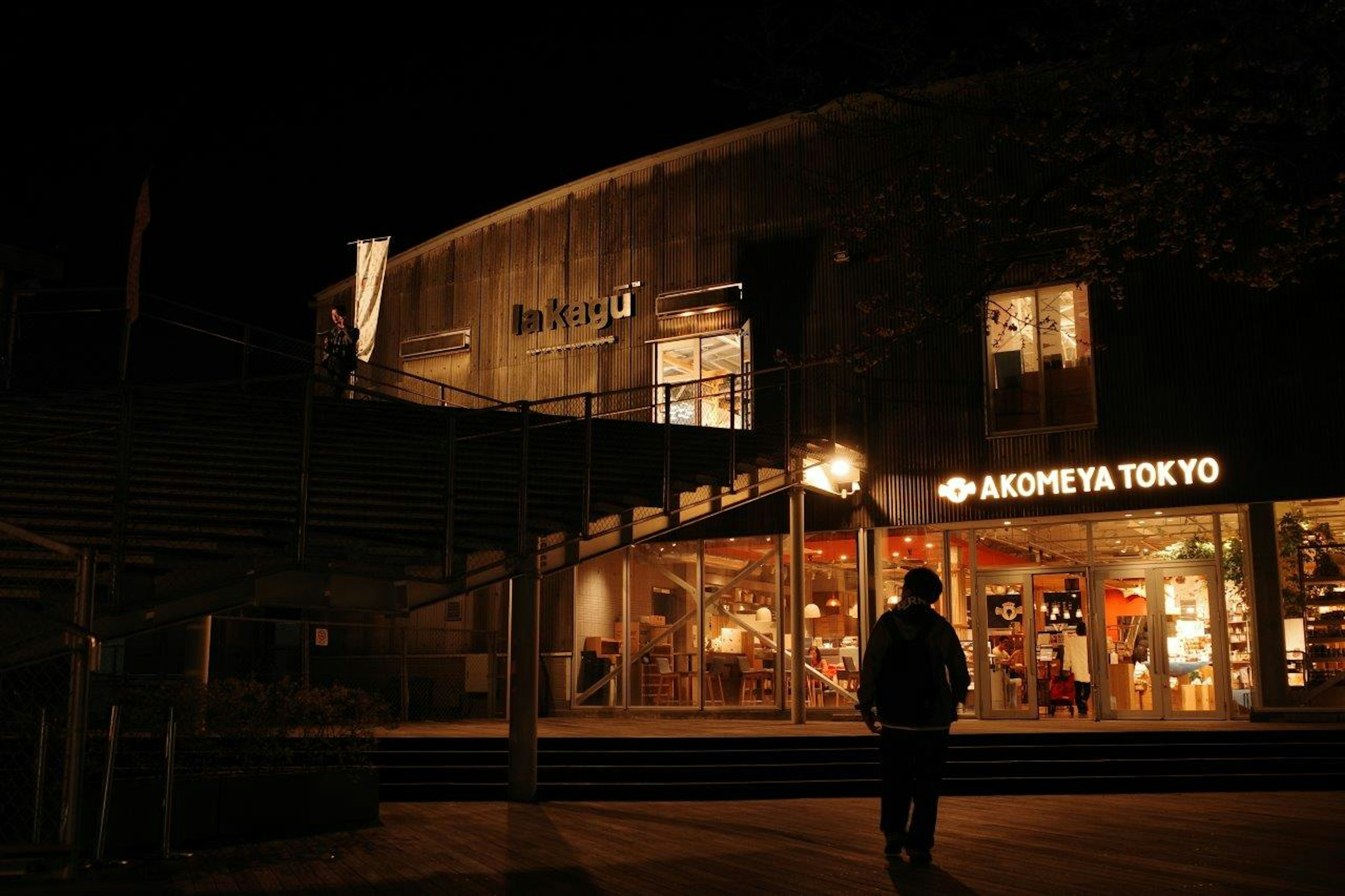 Escena nocturna de una tienda iluminada con la silueta de una persona en Tokio