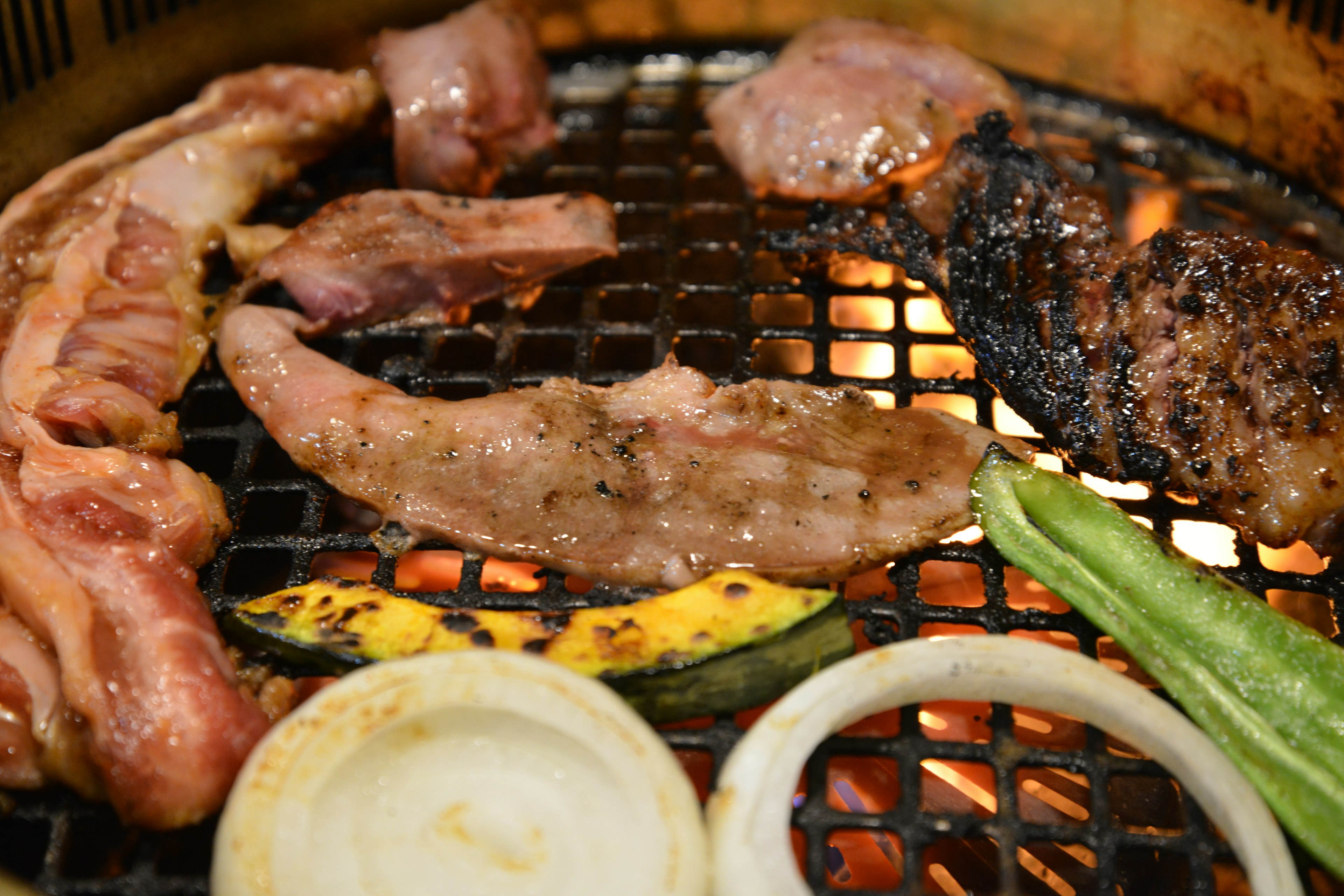 焼かれている肉と野菜が網の上に置かれているバーベキューのシーン