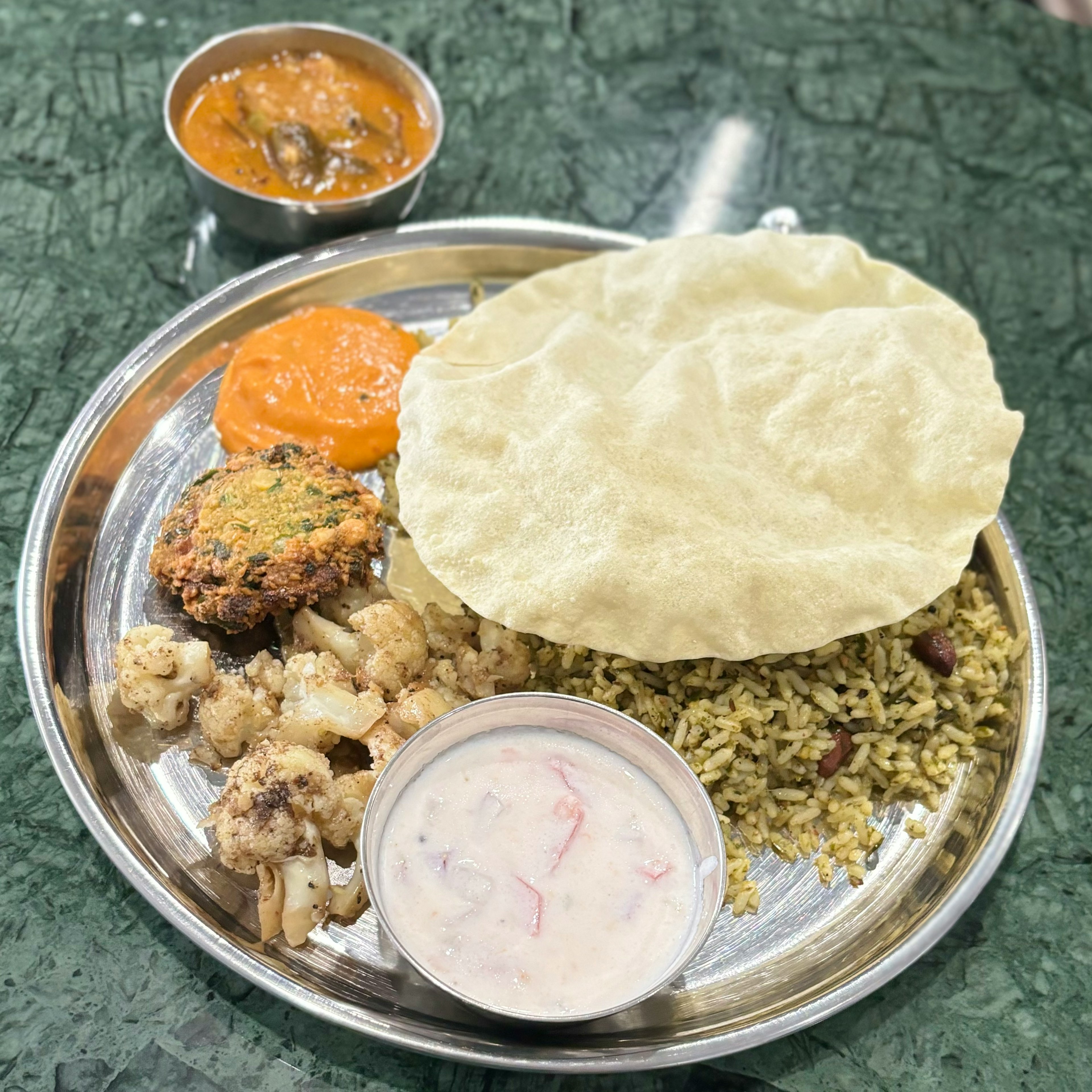 Un plato de cocina india con arroz, curry y varios acompañamientos