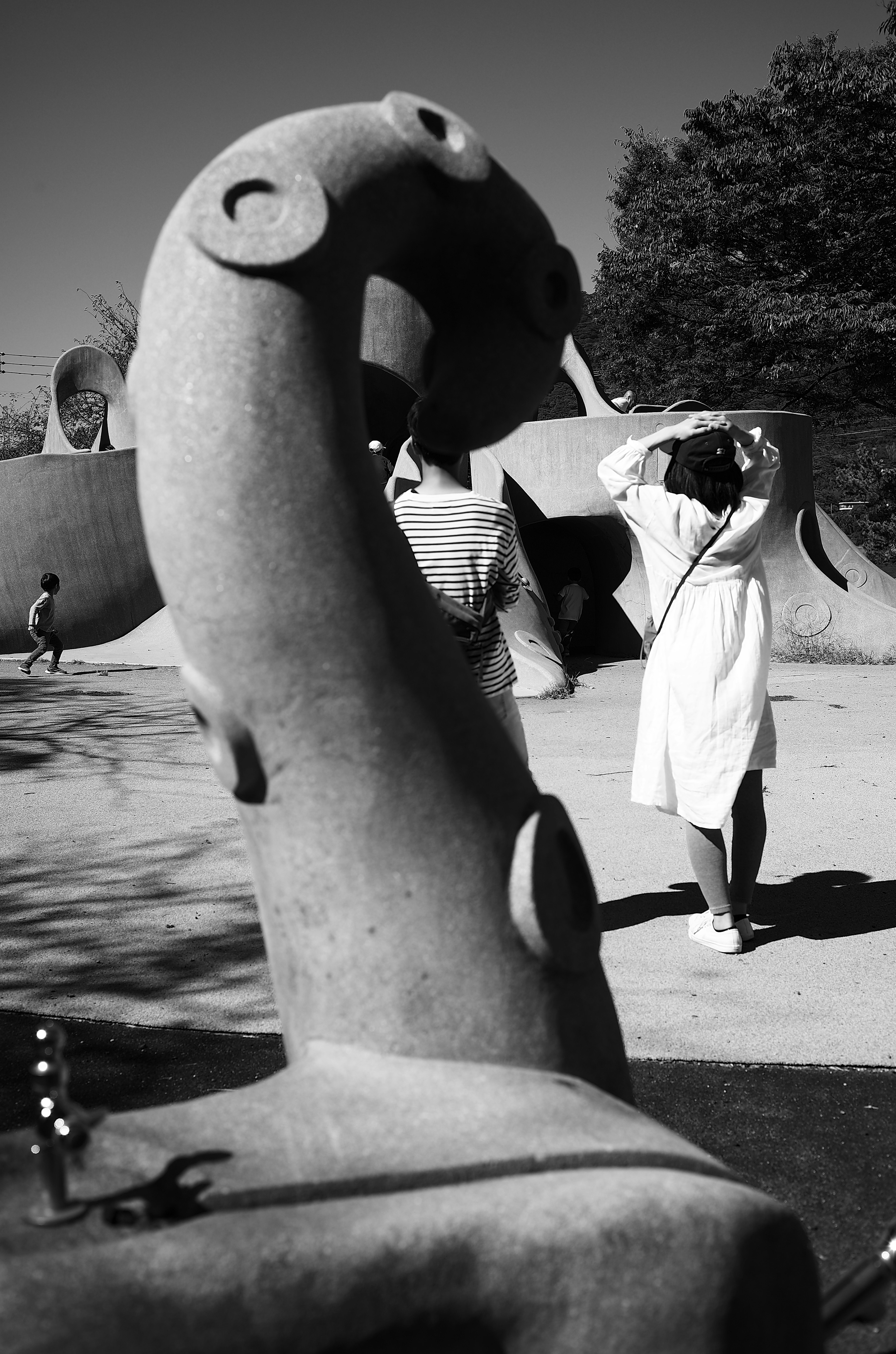 Sculpture de forme unique avec une personne en robe blanche contrastant dans la scène