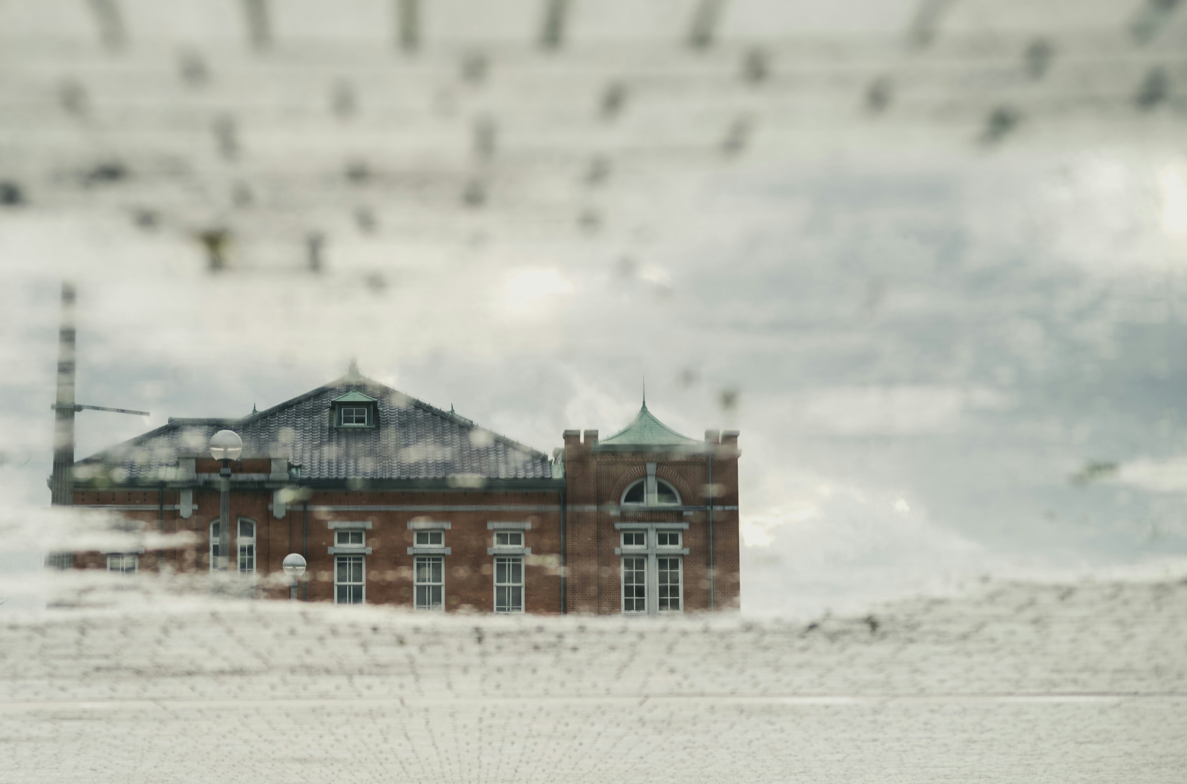 Historisches Backsteingebäude durch ein verschwommenes Fenster mit bewölktem Himmel gesehen