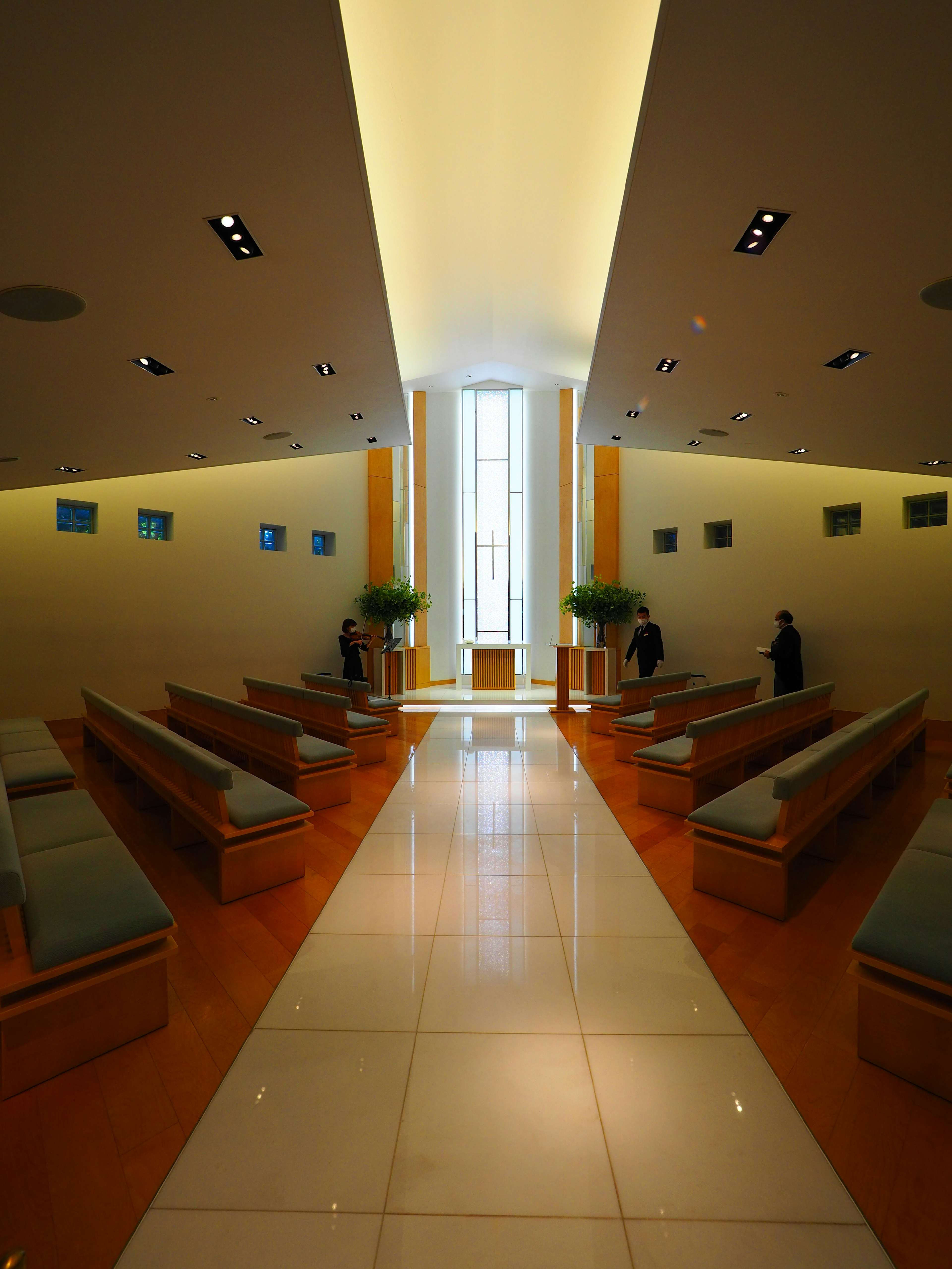 Interior of a modern chapel with bright light from large windows wooden benches lined up