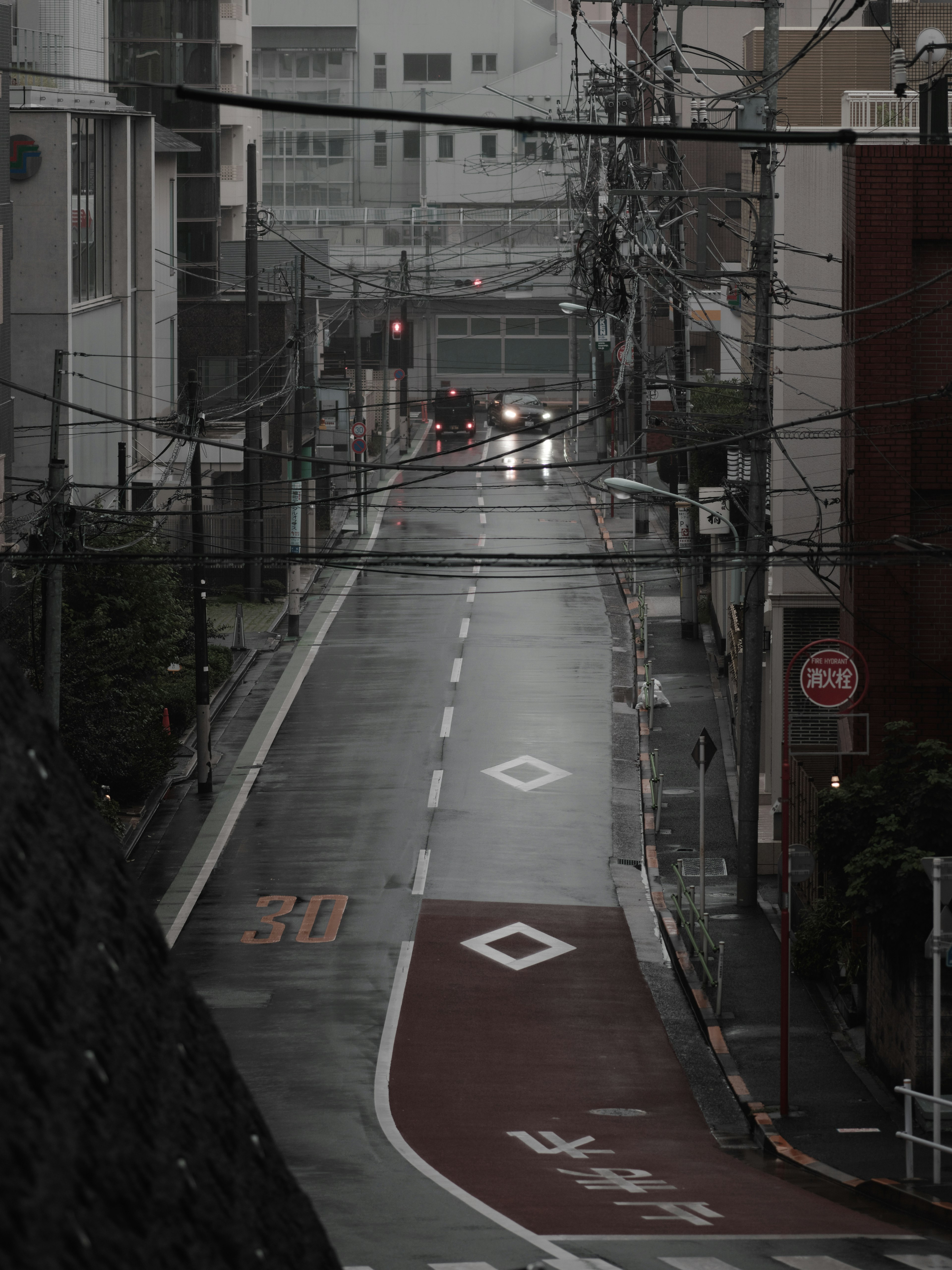 Quiet street in the rain with faint car headlights visible