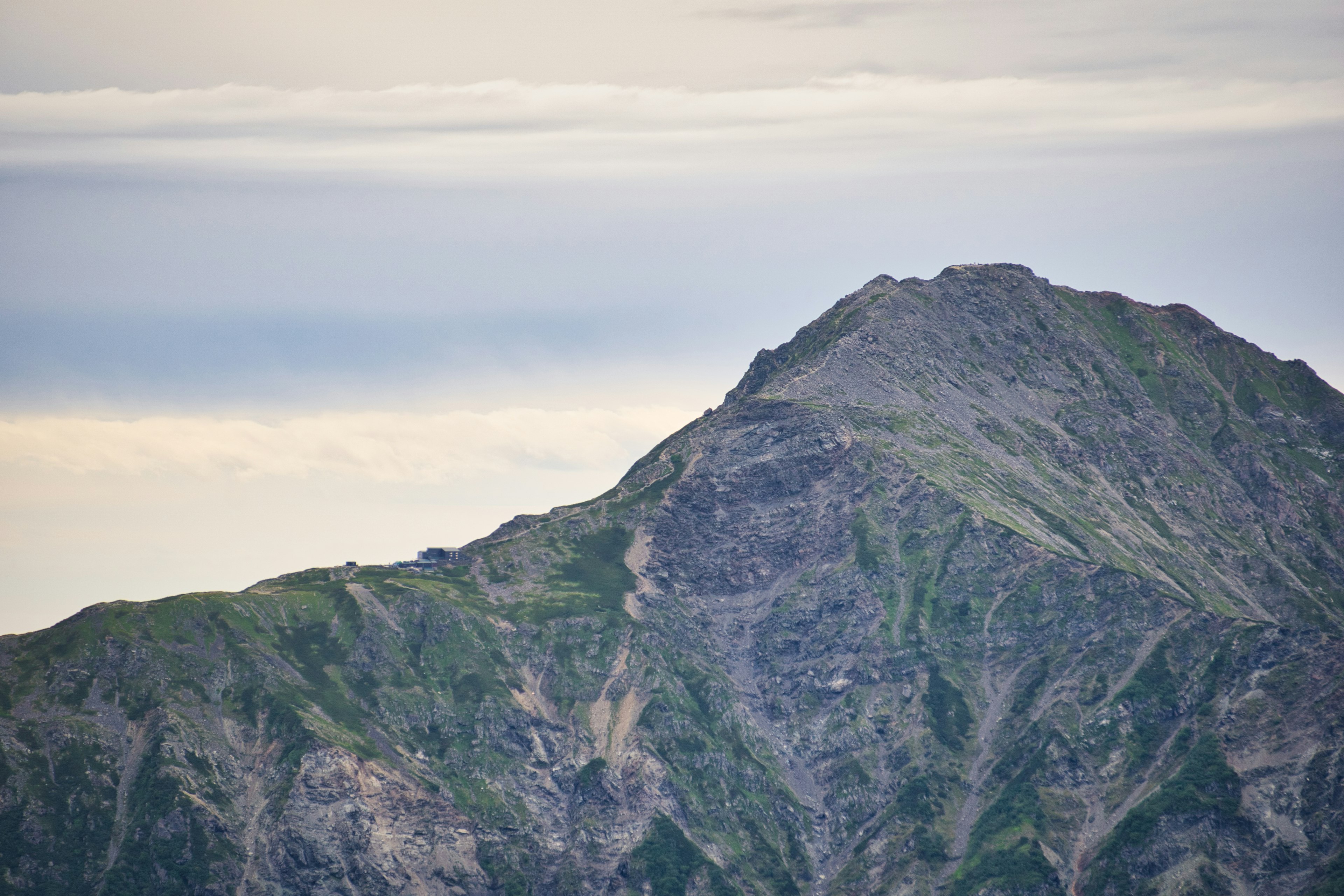 山の頂上が見える風景 緑の斜面と岩肌のコントラスト