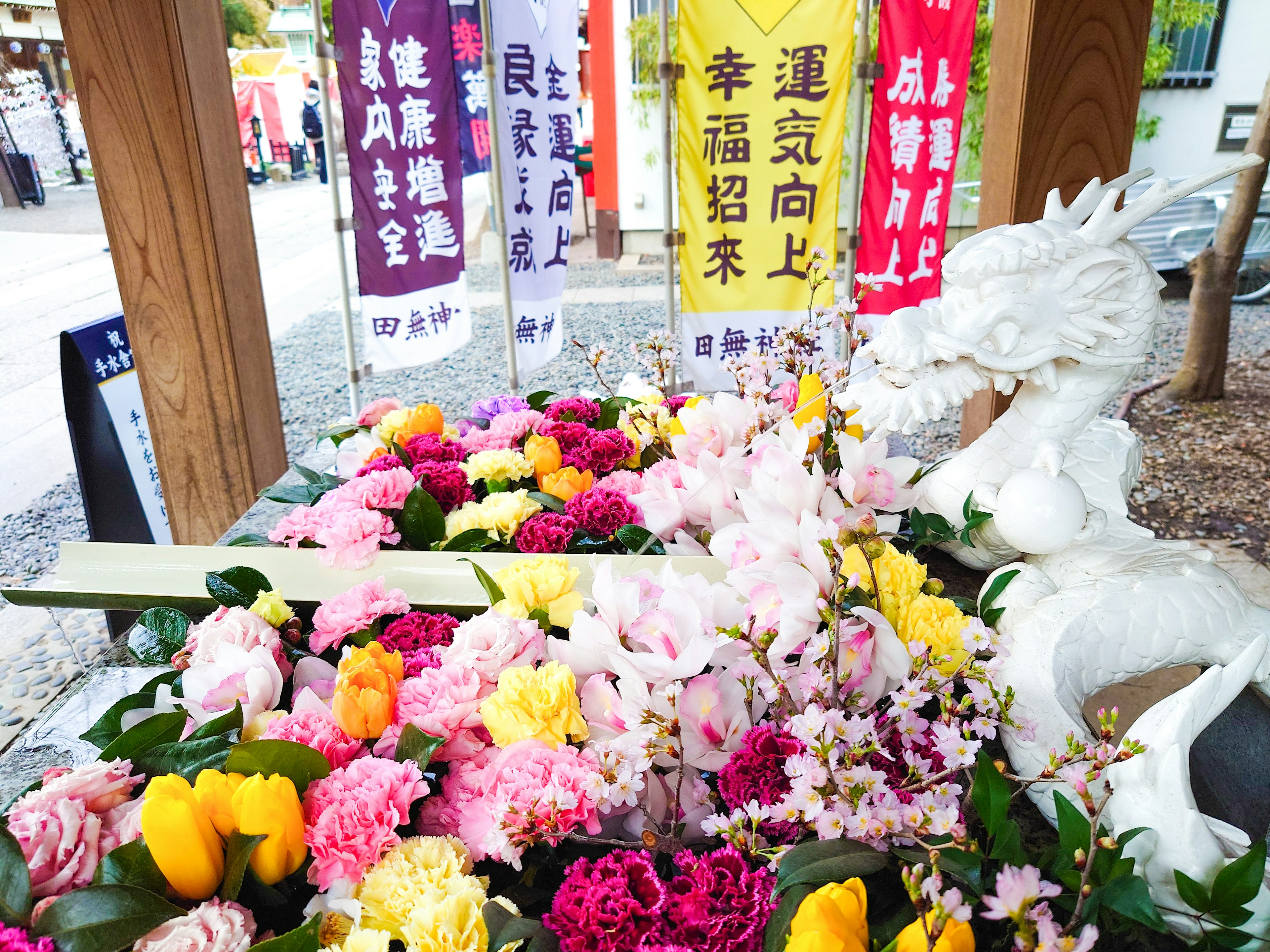 花と白いドラゴンの彫刻がある祭壇に色とりどりの花が並ぶ風景