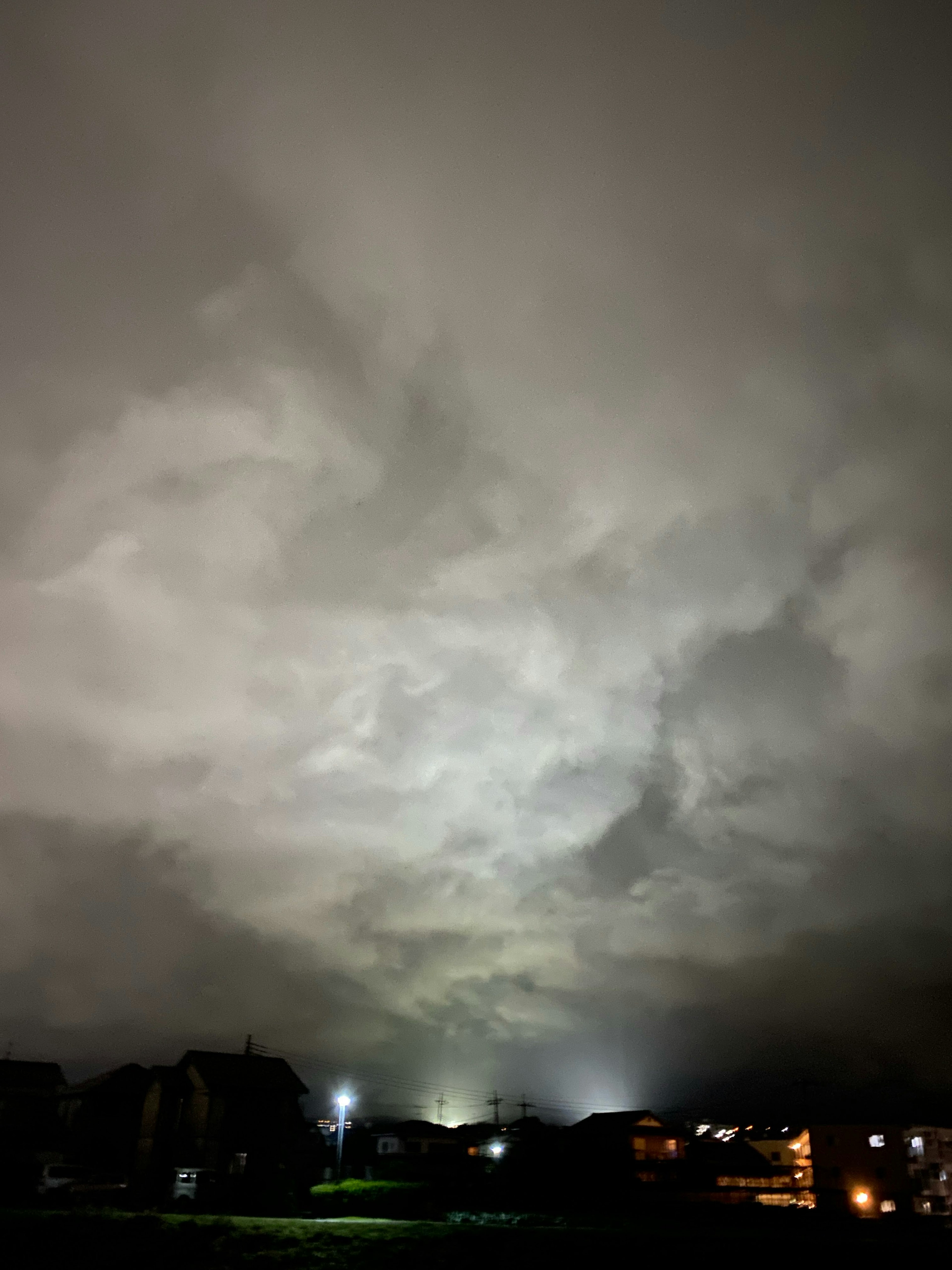 Cielo oscuro con nubes en espiral y luces distantes