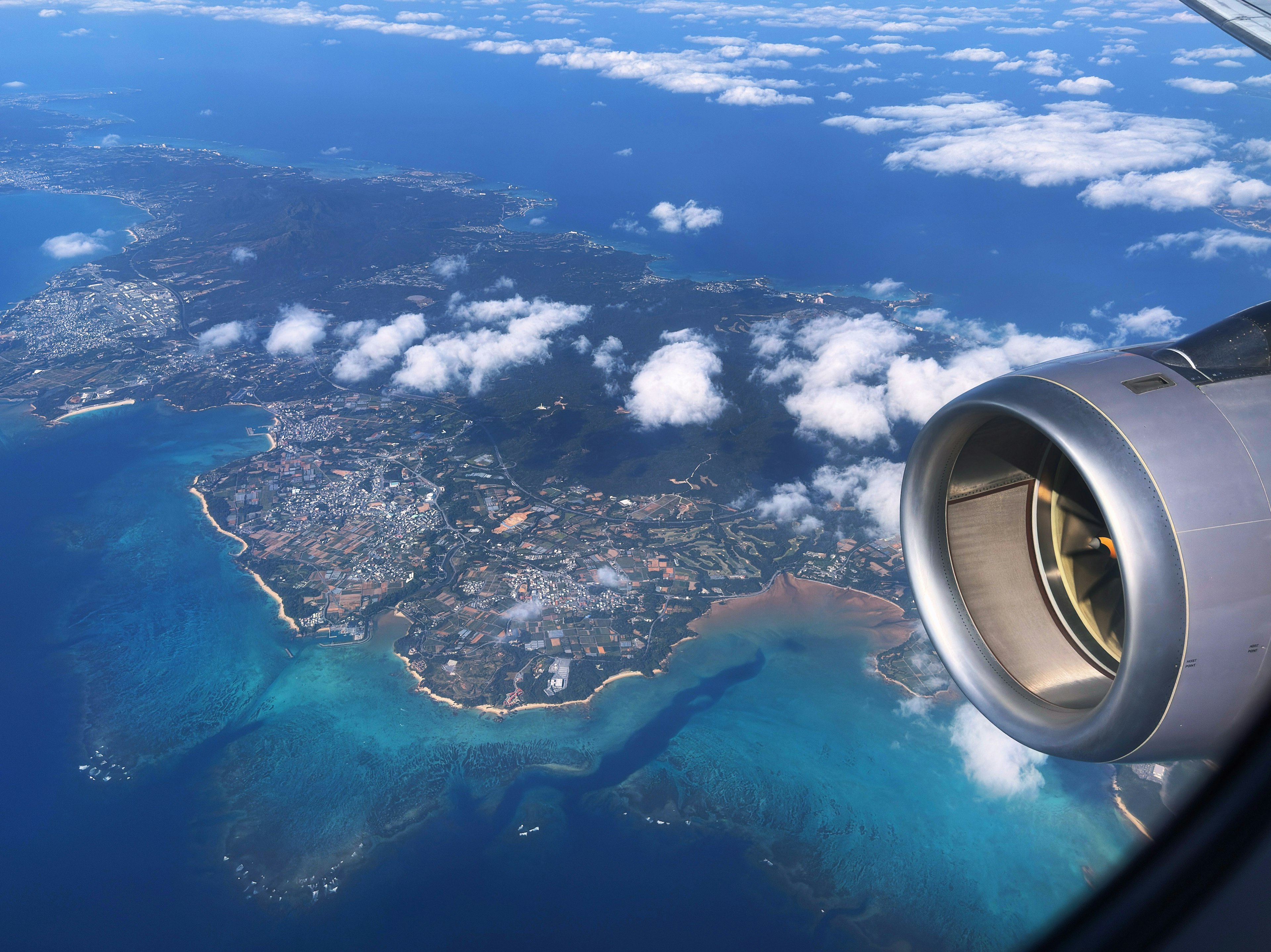 Vista aérea de una isla con aguas azules y motor de avión