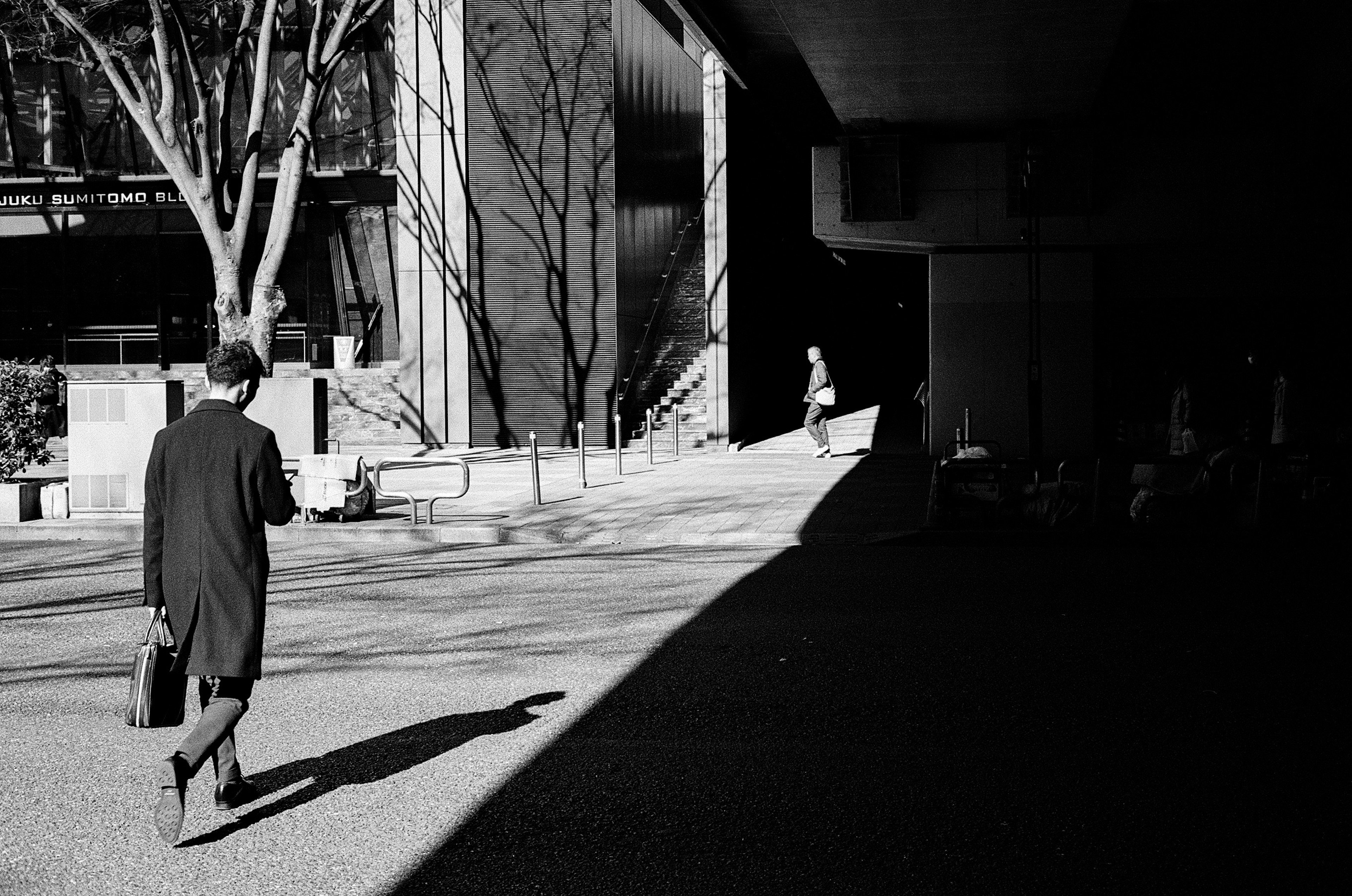 Un homme d'affaires en manteau noir marchant dans un cadre urbain monochrome