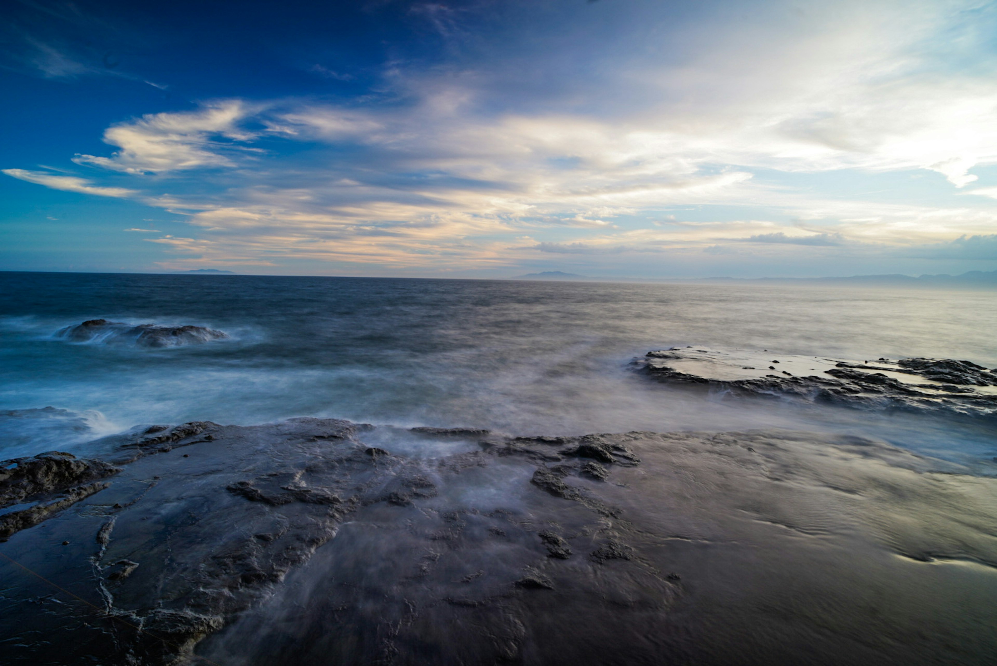 Panoramic view of coastal rocks and blue sky