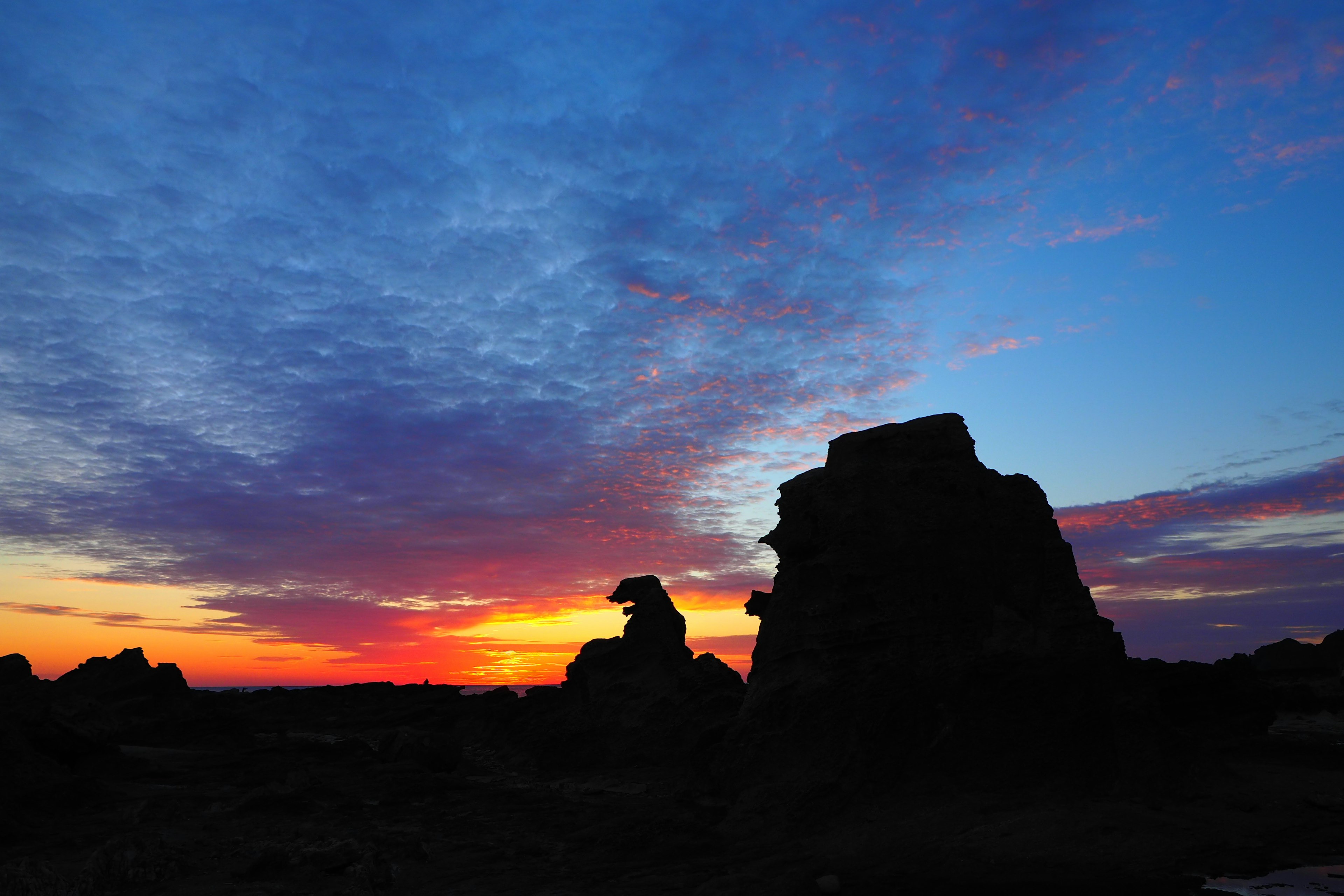 Silhouette von Felsen gegen einen lebhaften Sonnenuntergangshimmel