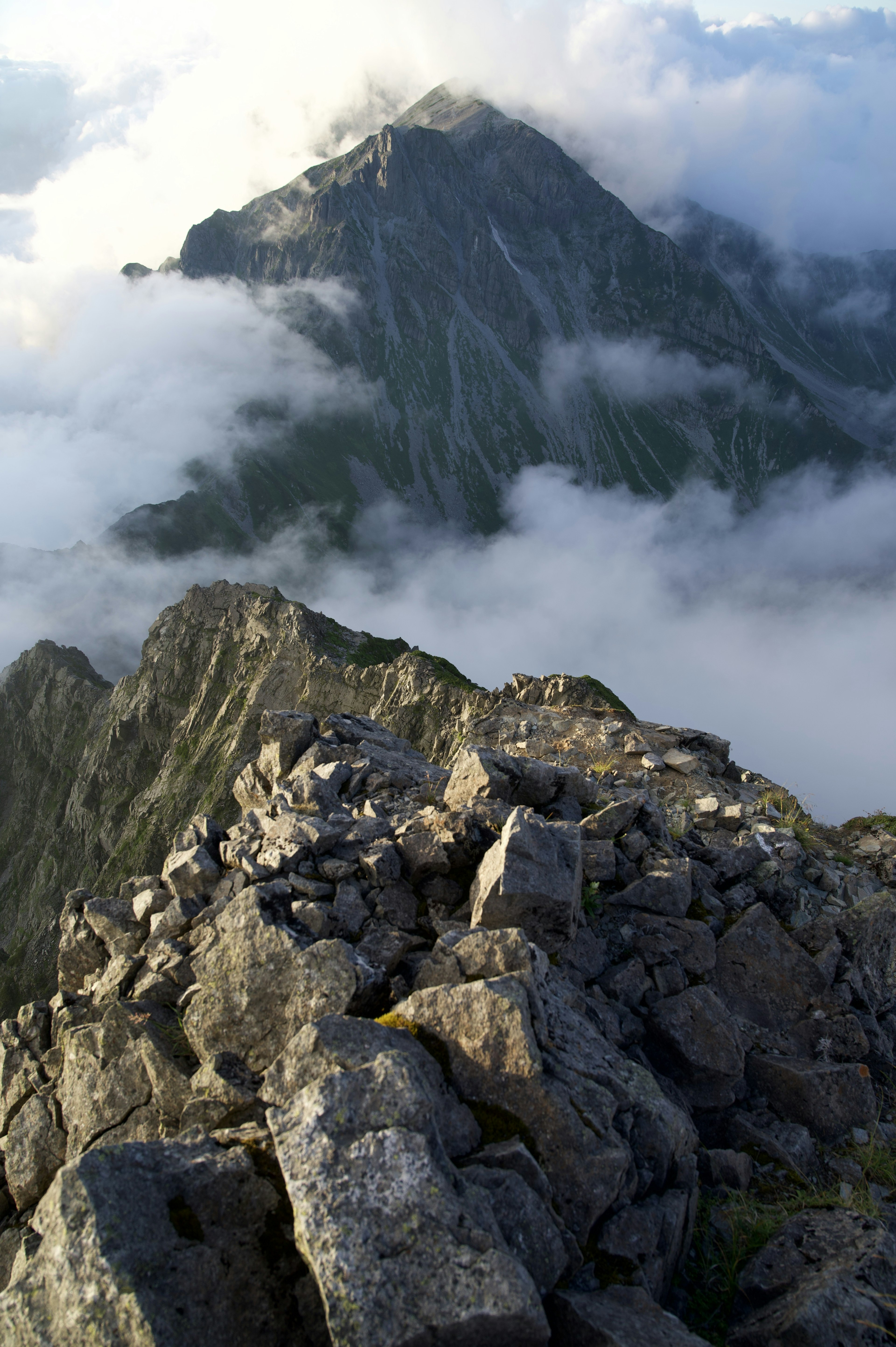 Vista escénica desde la cima de la montaña con terreno rocoso y nubes