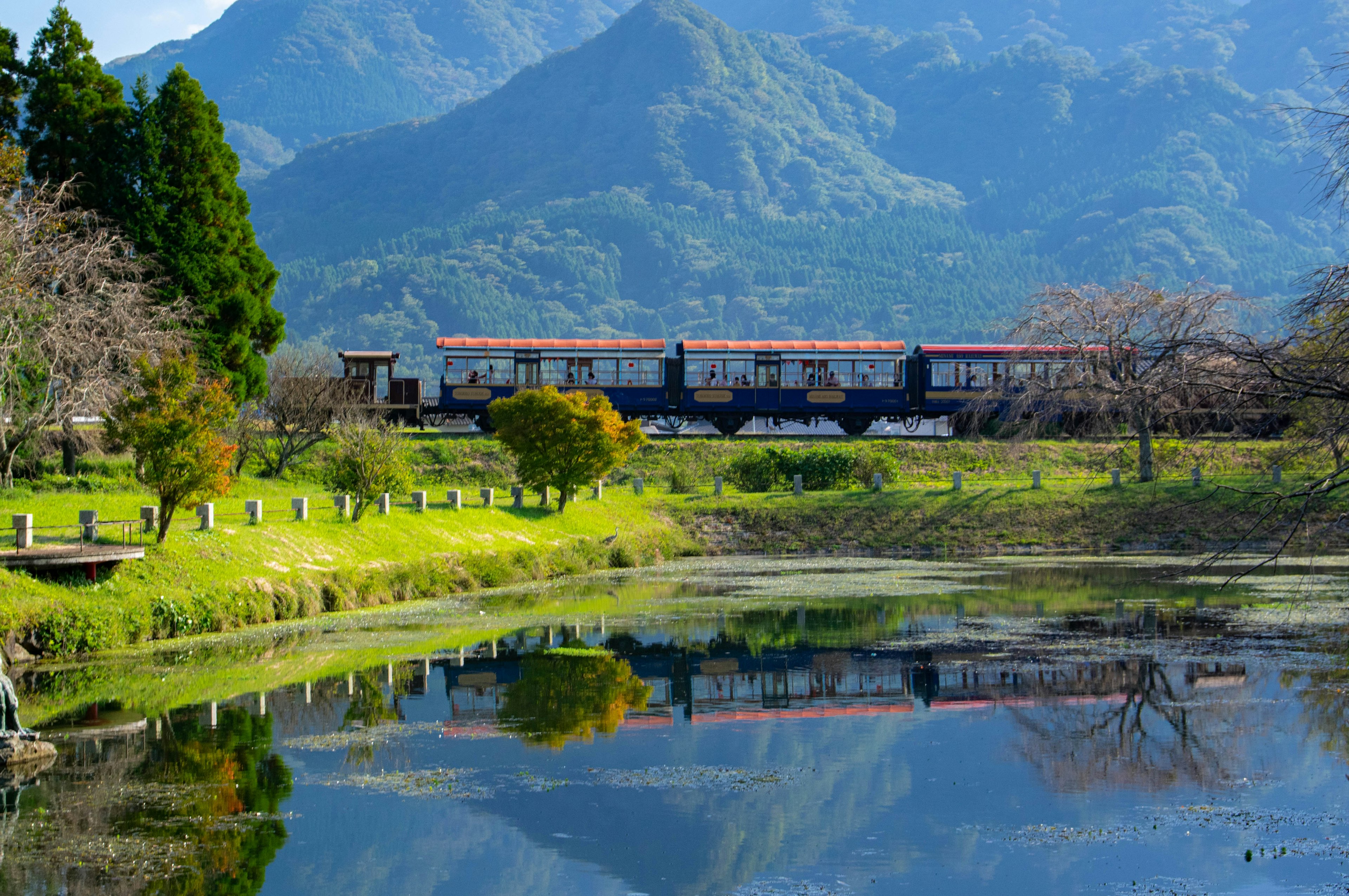 一列火車在寧靜的湖邊穿行，四周環繞著山脈的美麗景色