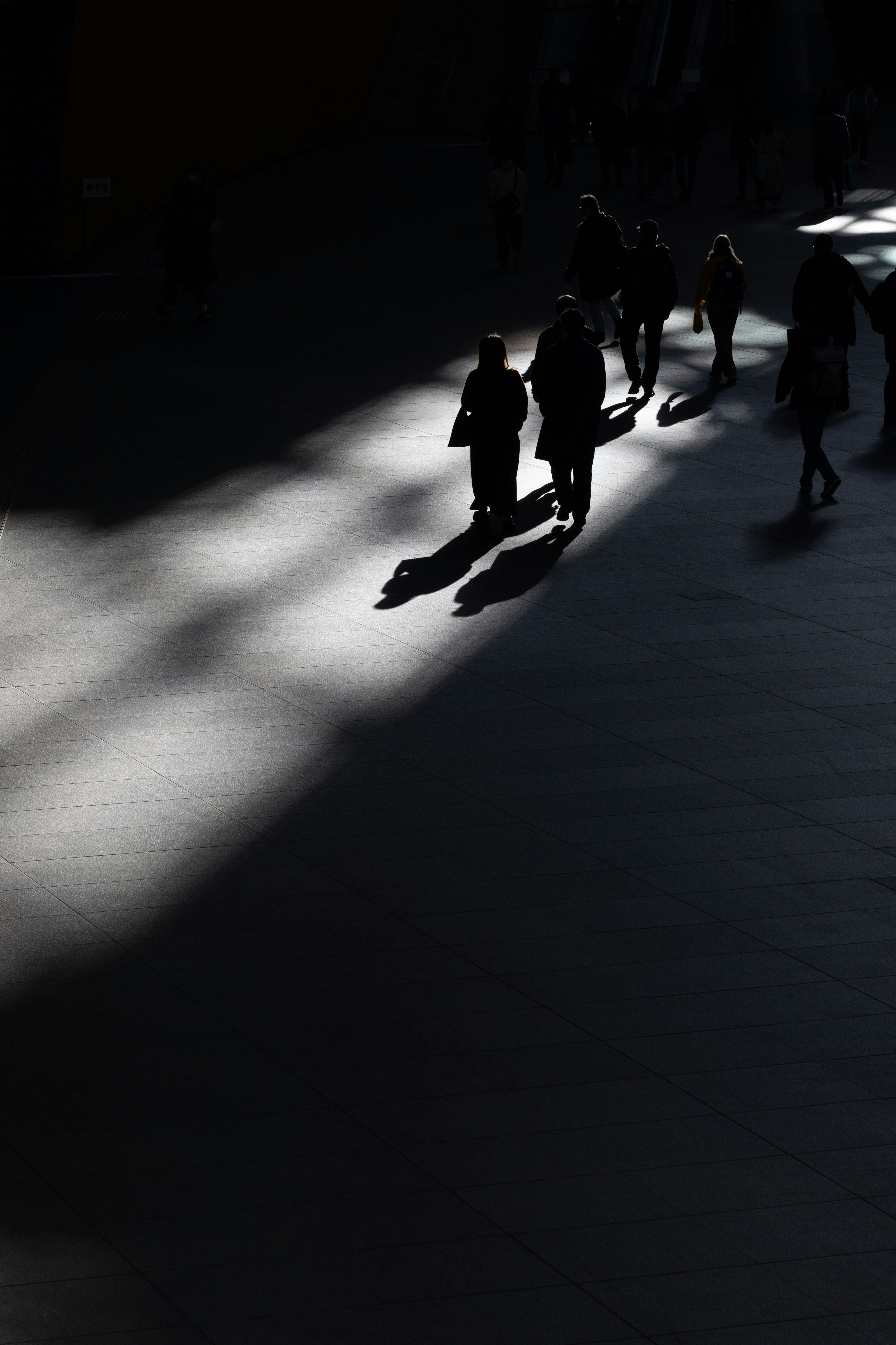 Siluetas de personas caminando en sombras sobre un fondo oscuro