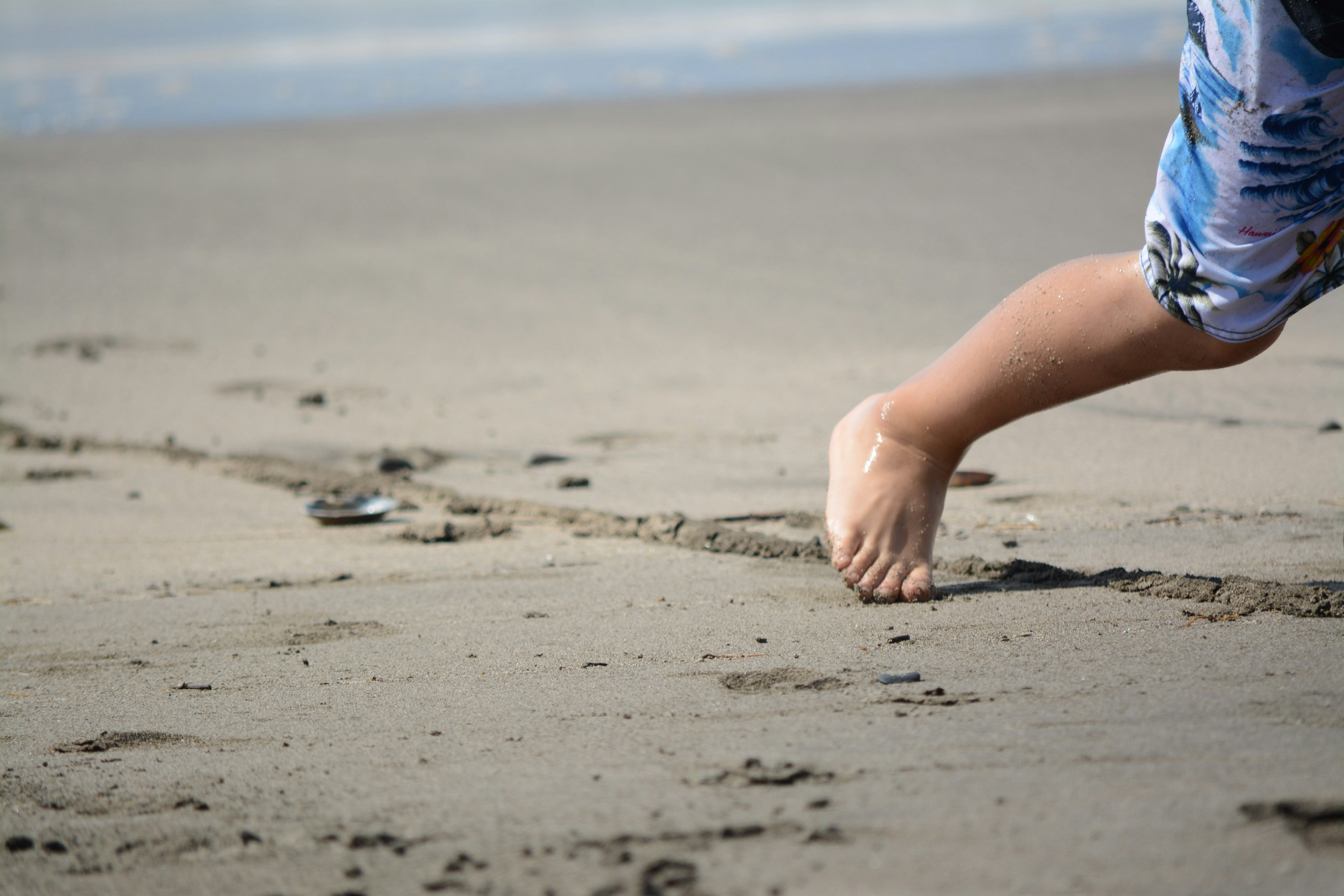 Child's foot making footprints on sandy beach