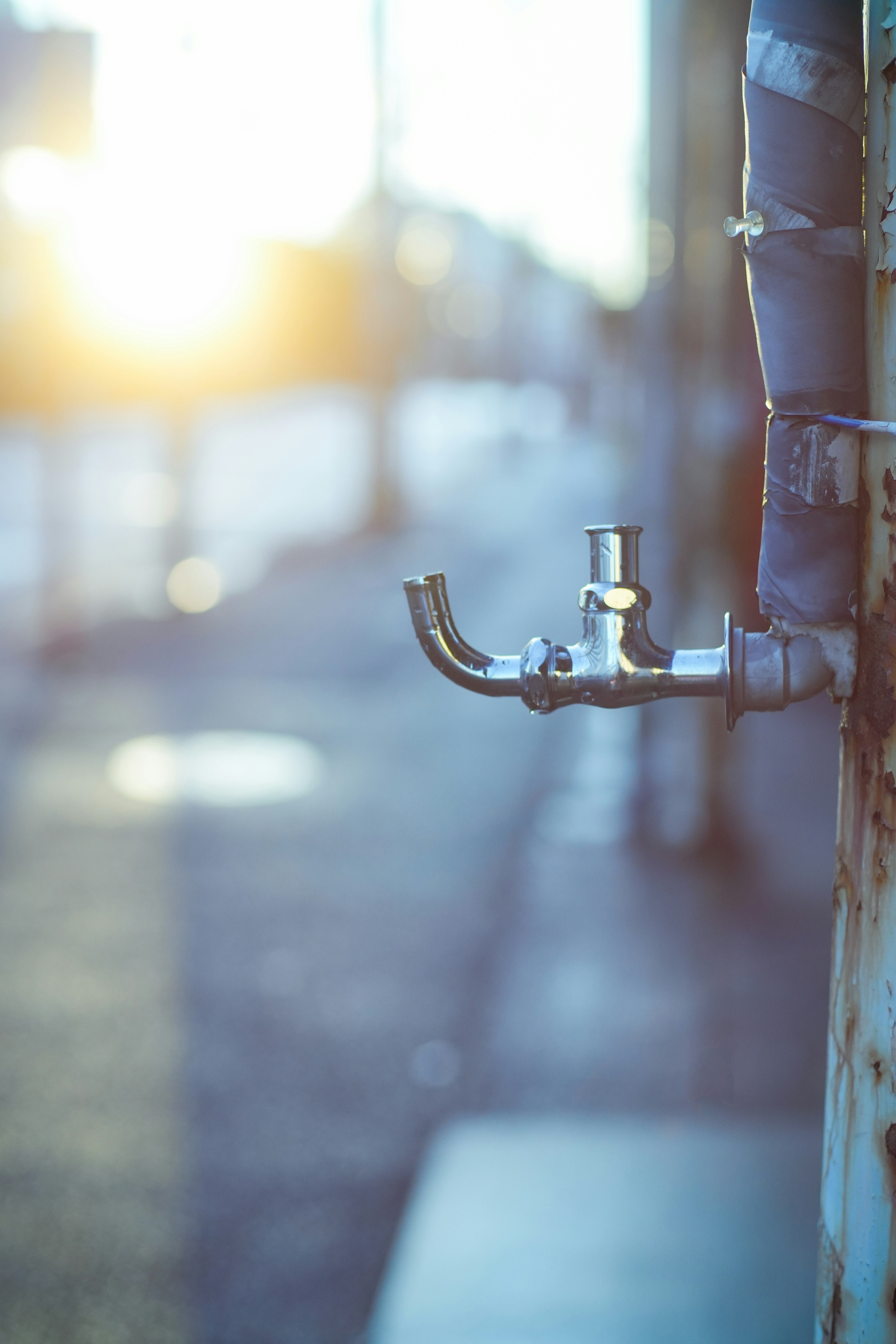 Urban water faucet with sunset background