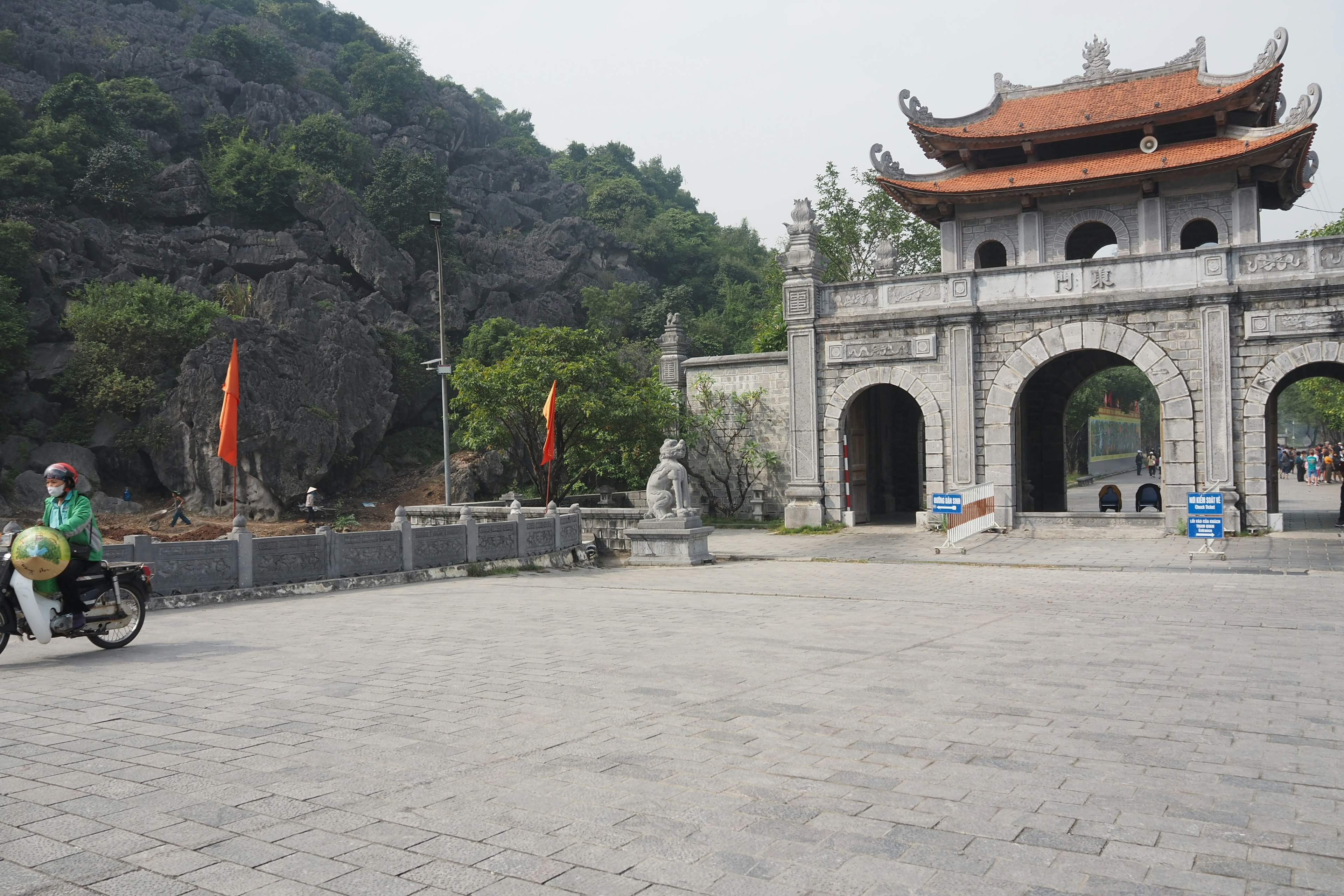 Old stone gate near a mountain with a person on a bicycle