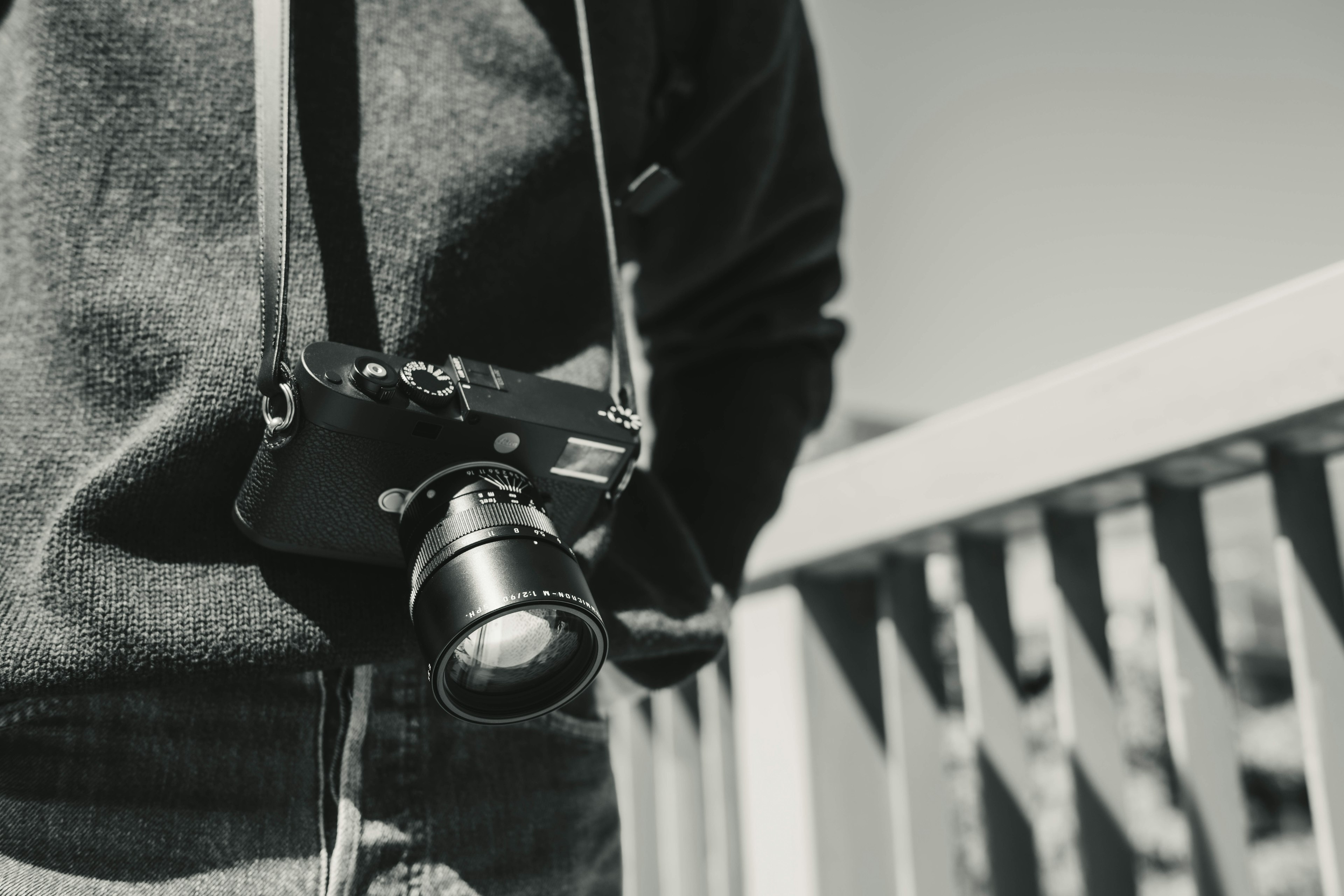 Photo en noir et blanc d'un homme avec un appareil photo autour du cou