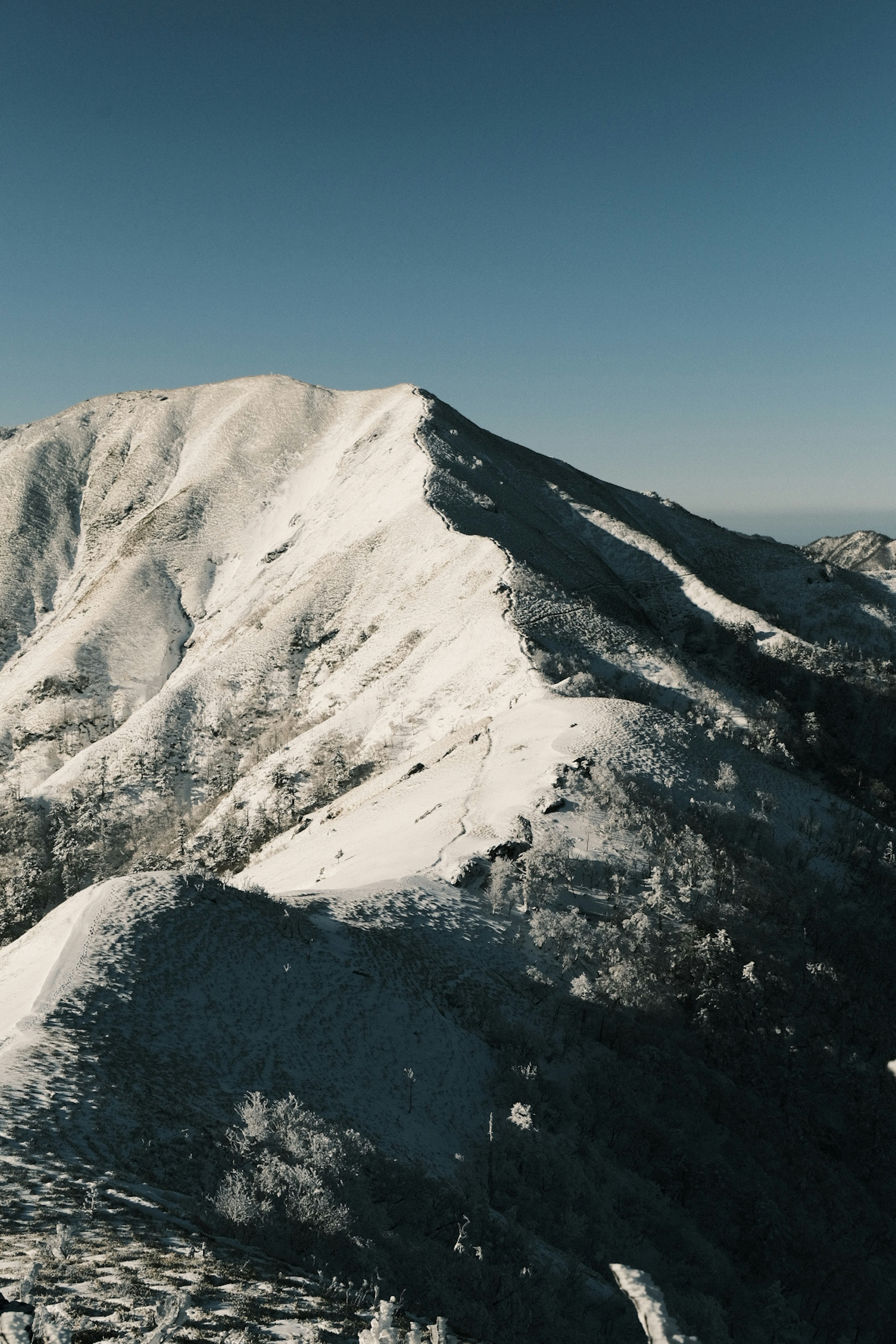 Paesaggio montano innevato sotto un cielo blu chiaro