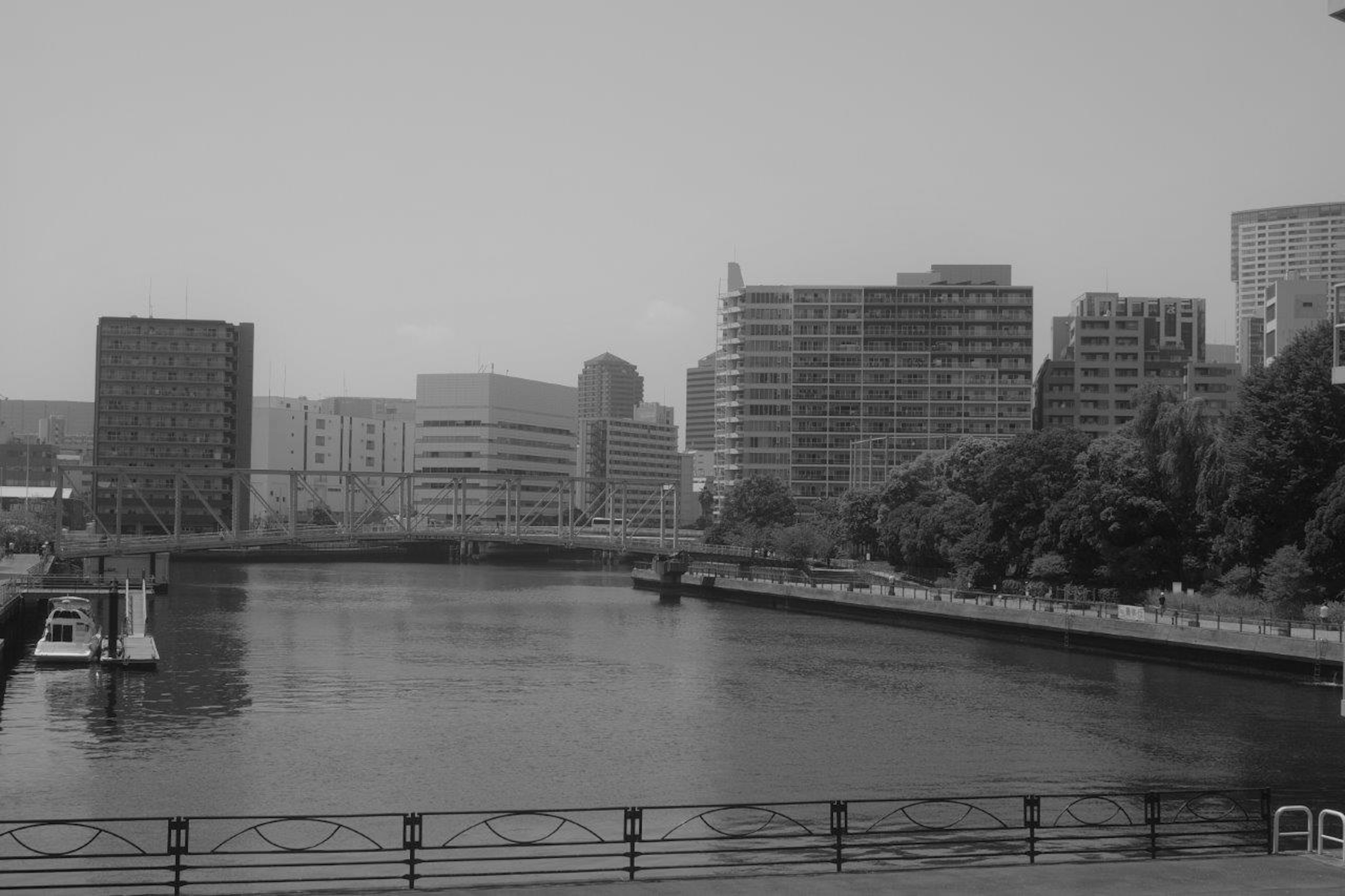 Black and white image of a river with urban landscape