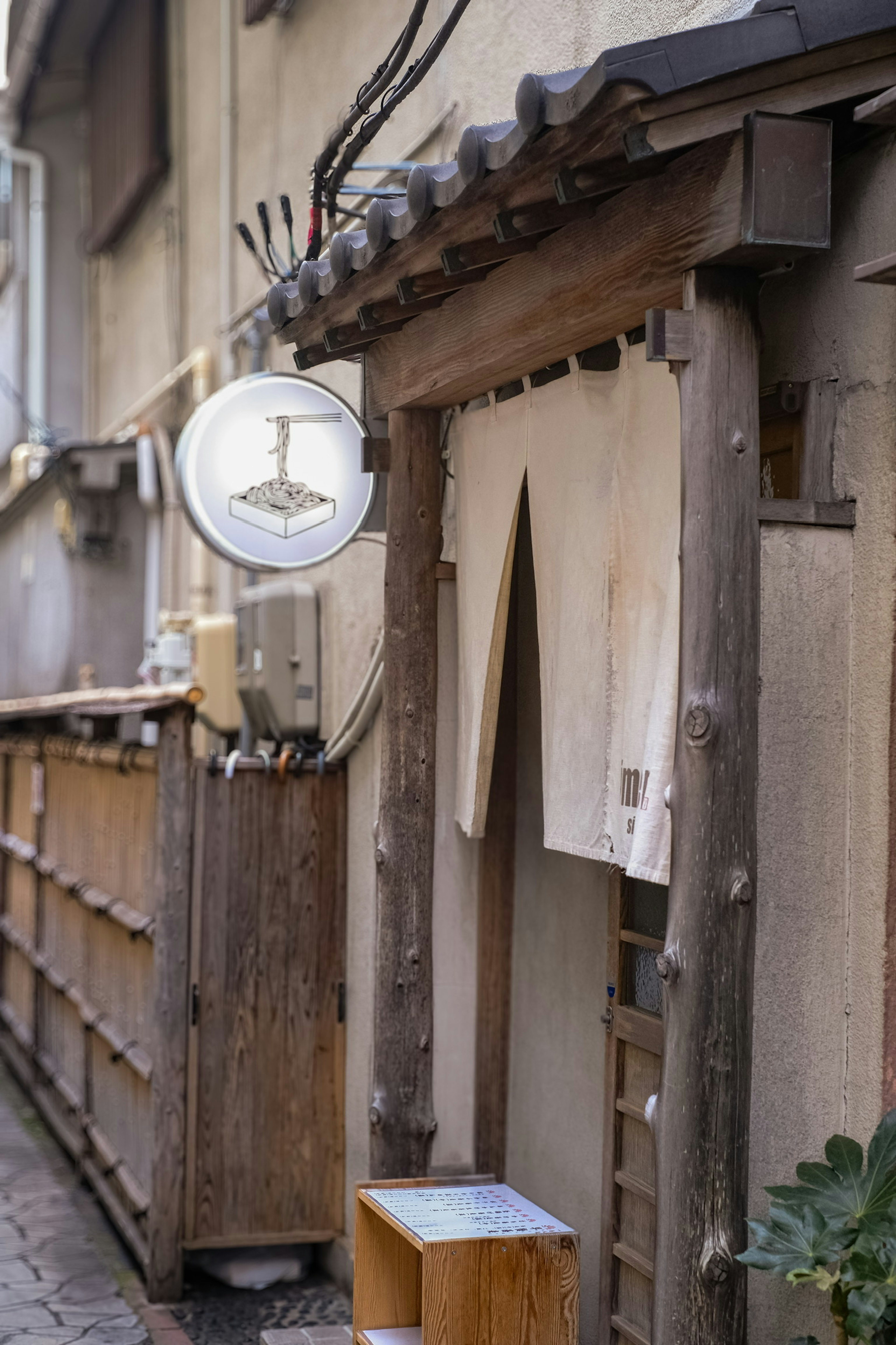 Exterior of an old Japanese house with a wooden door and a noren curtain