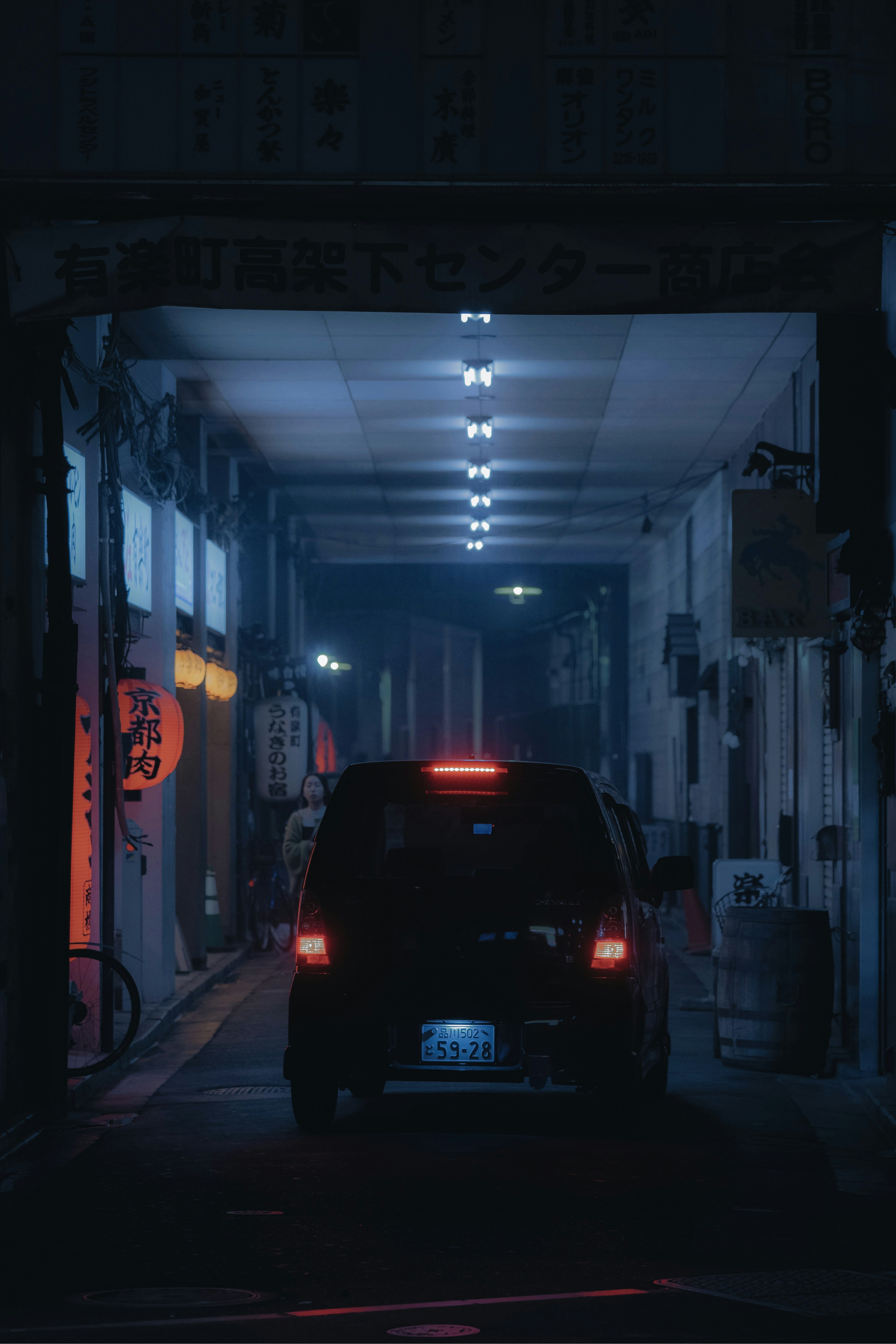 Rear view of a car parked in a dark alley with bright lights