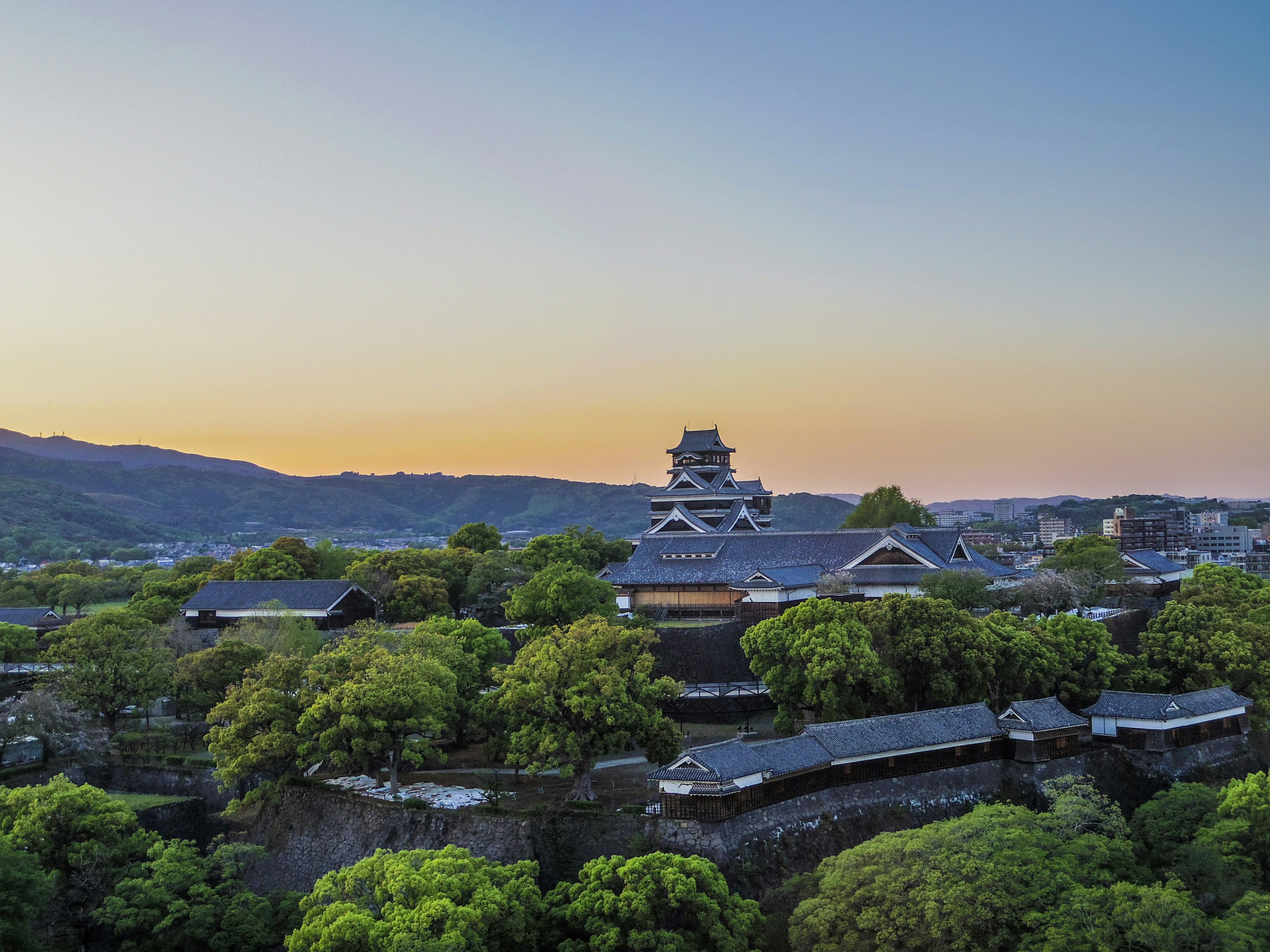 熊本城と緑豊かな木々の景観が広がる夕暮れ時の風景