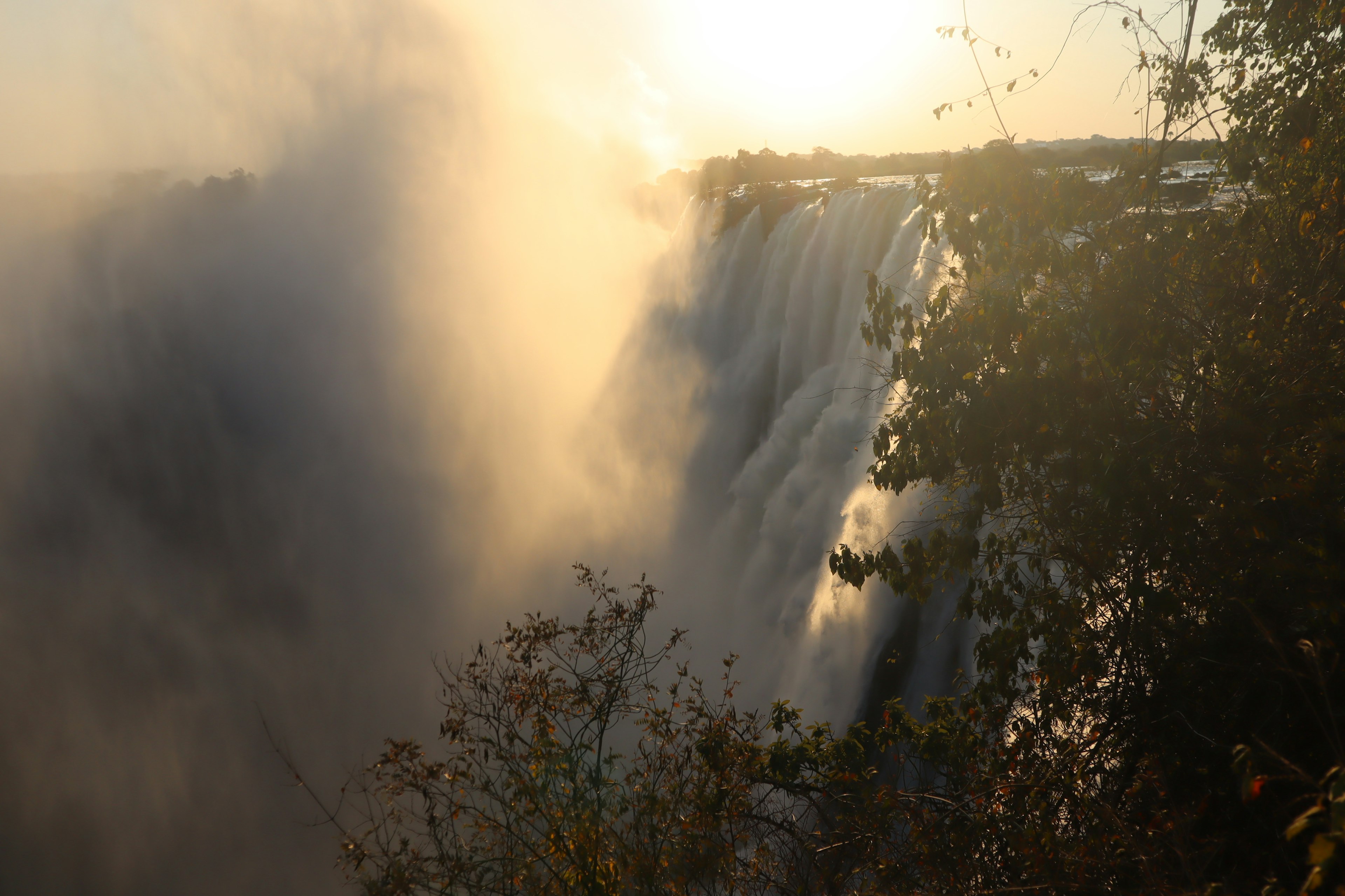 Vista maestosa della cascata con nebbia e sole al tramonto