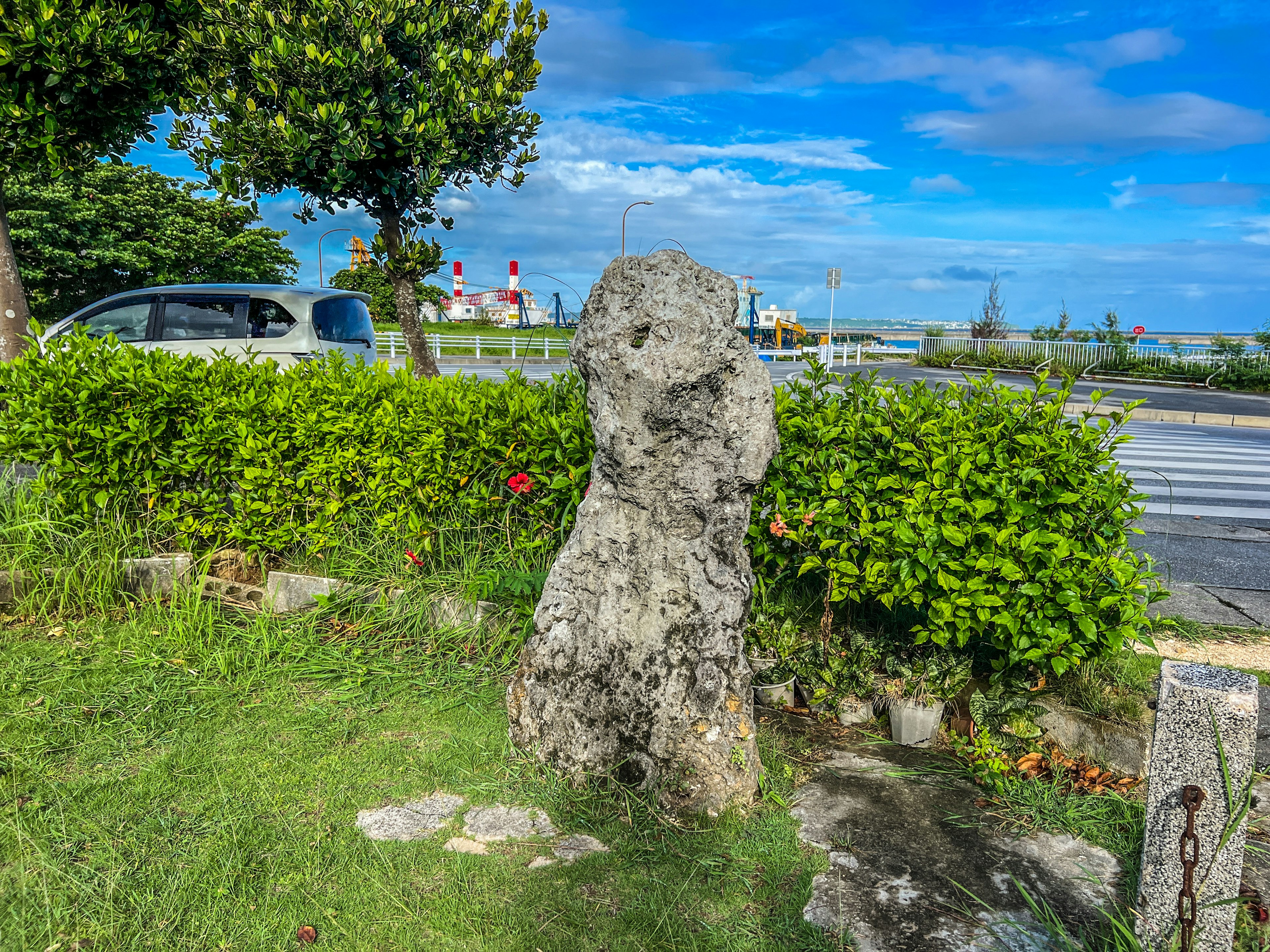 Große Steinskulptur umgeben von grünen Pflanzen und blauem Himmel