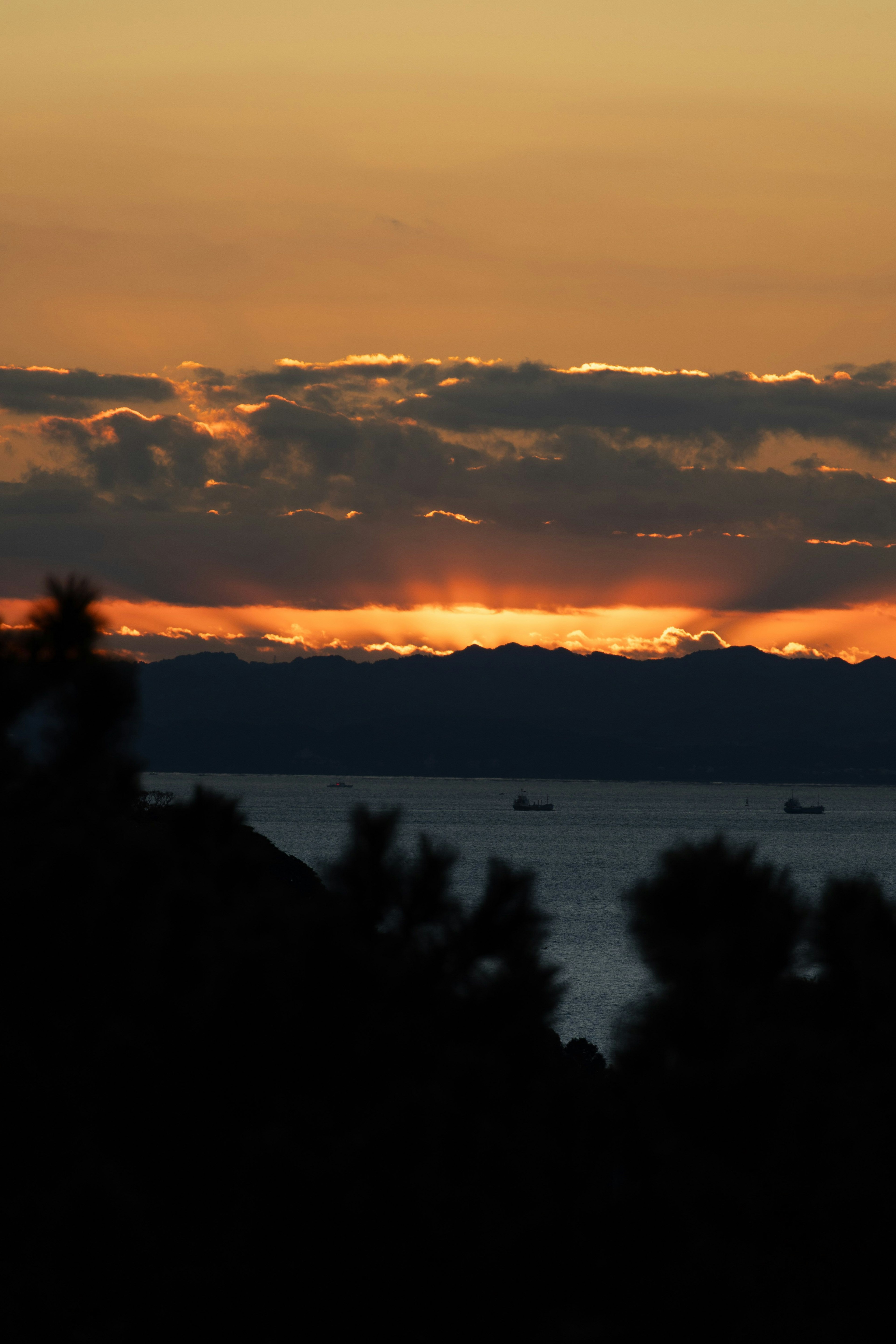夕焼けの海の景色と山々のシルエット