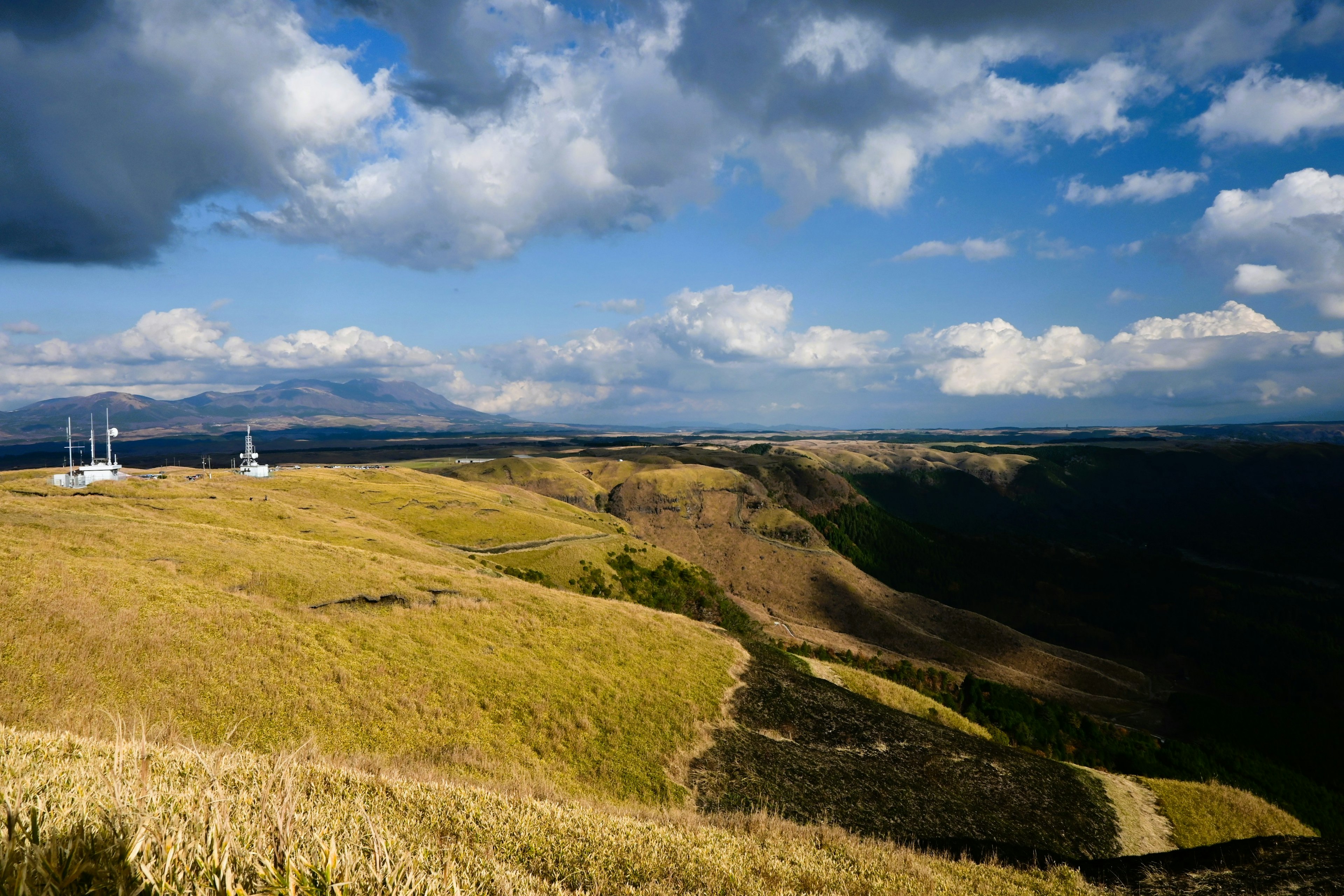 Weite Graslandschaft mit blauem Himmel und weißen Windturbinen