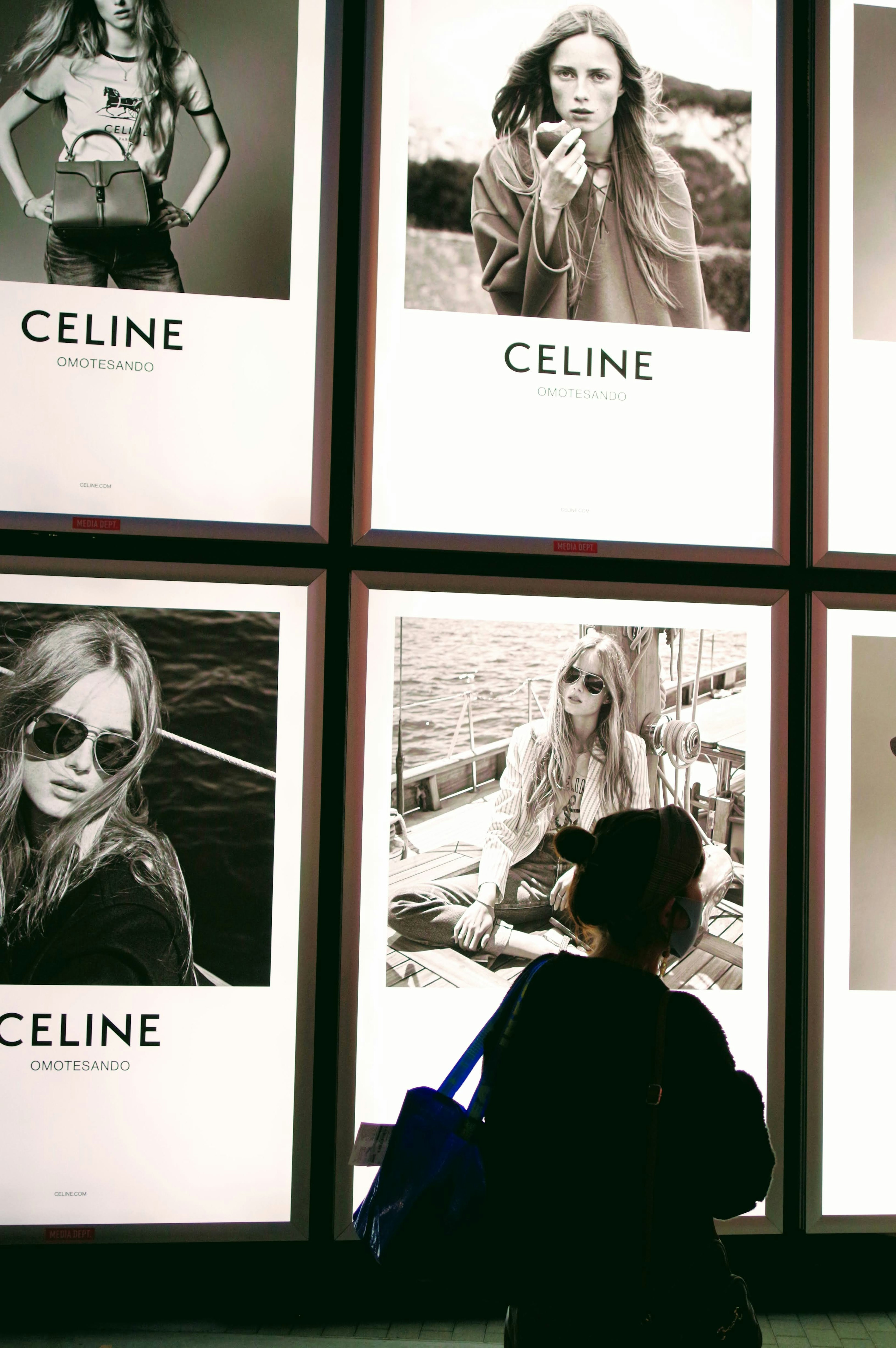 Una mujer admirando anuncios de Celine con retratos de moda en blanco y negro