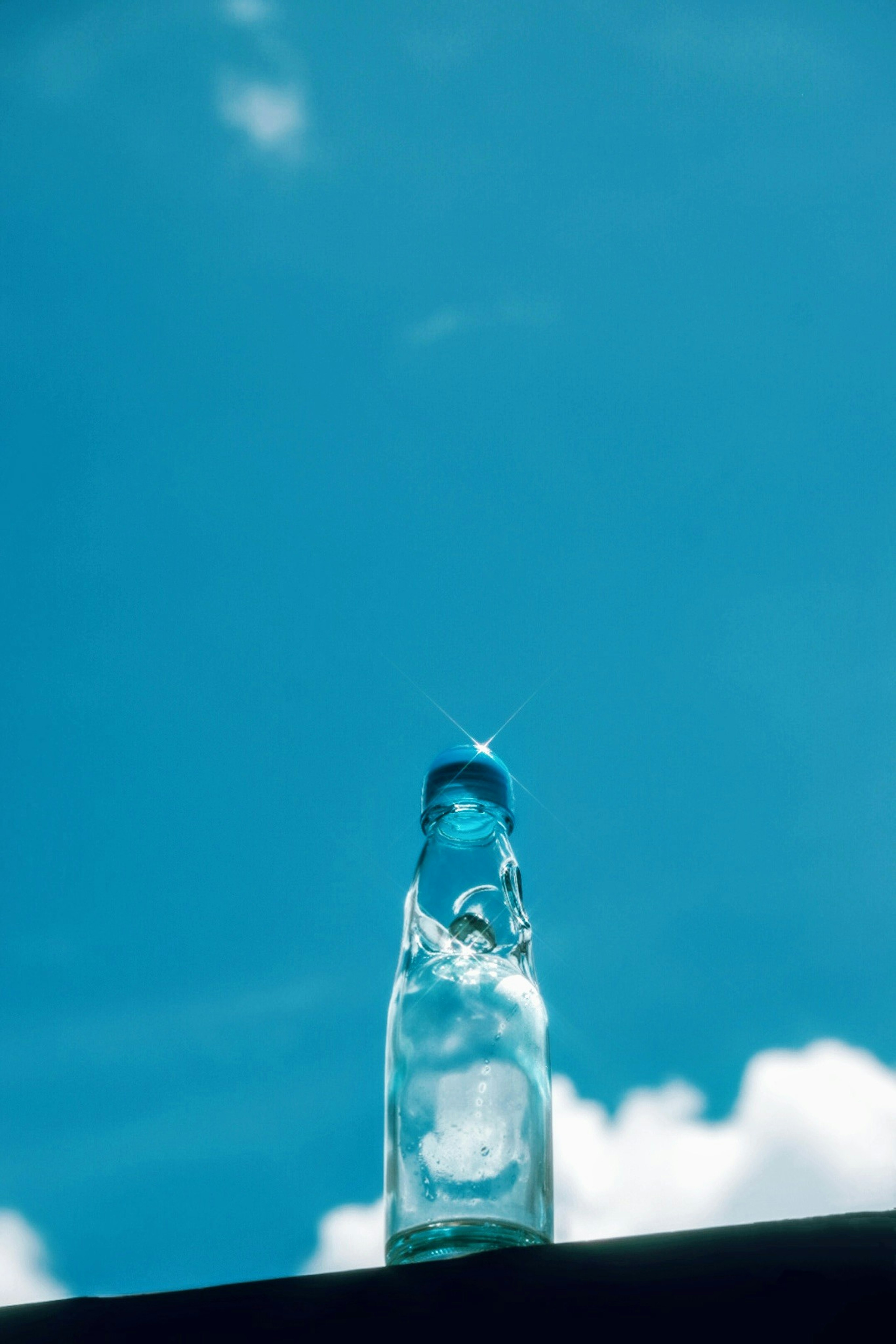 Bottiglia trasparente con acqua contro un cielo blu