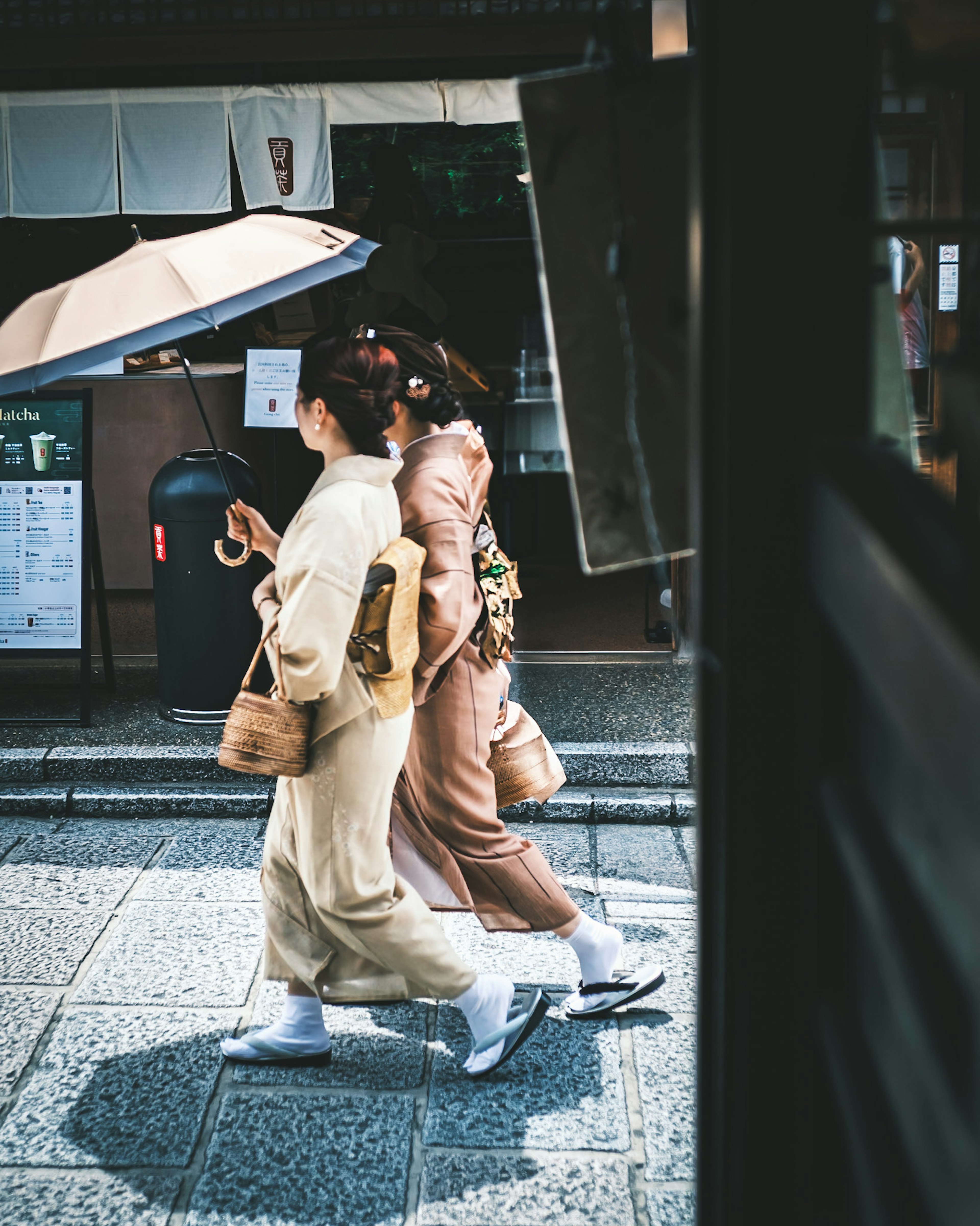 Two women walking in traditional kimonos with an umbrella