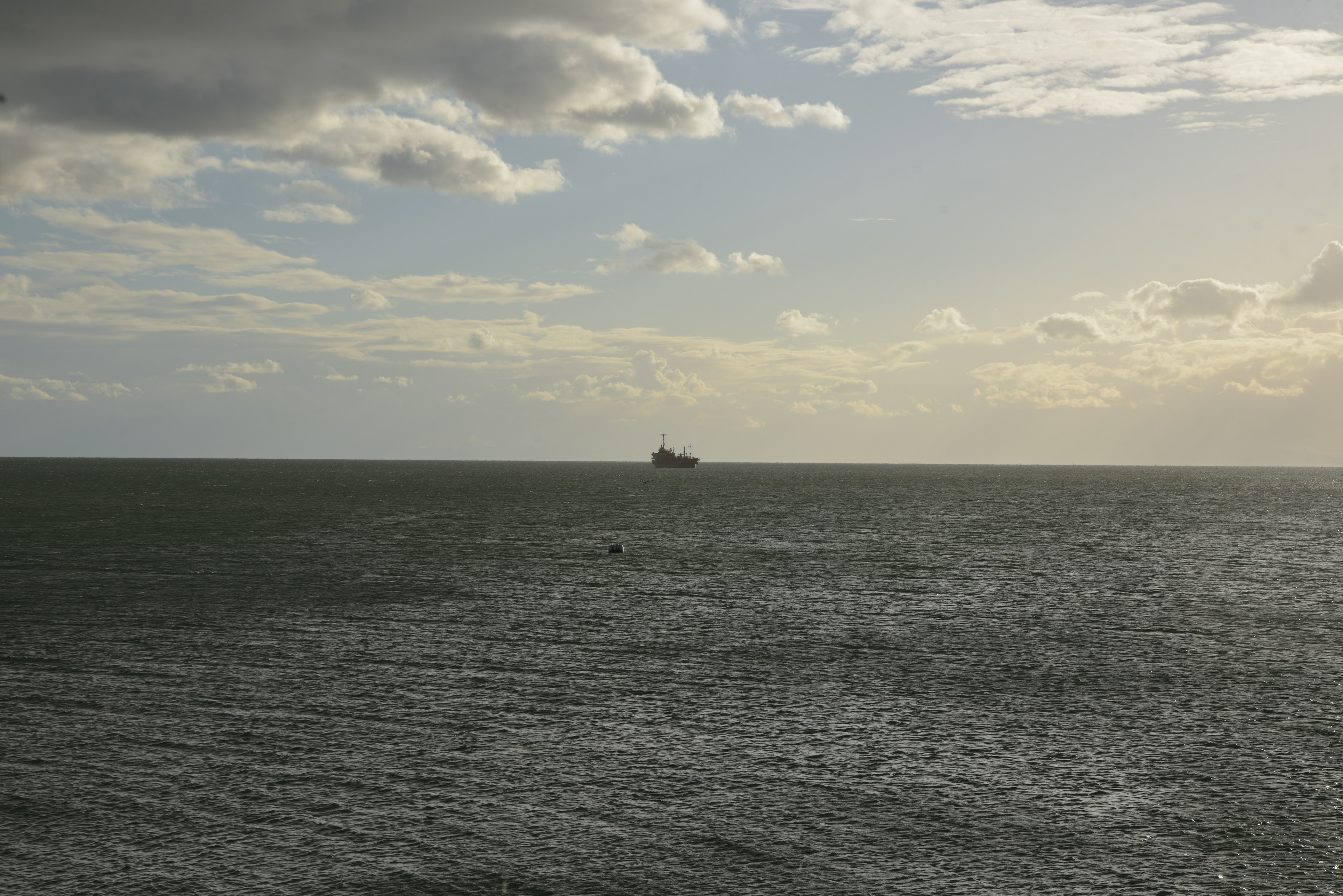 A ship floating on the ocean with expansive clouds in the background