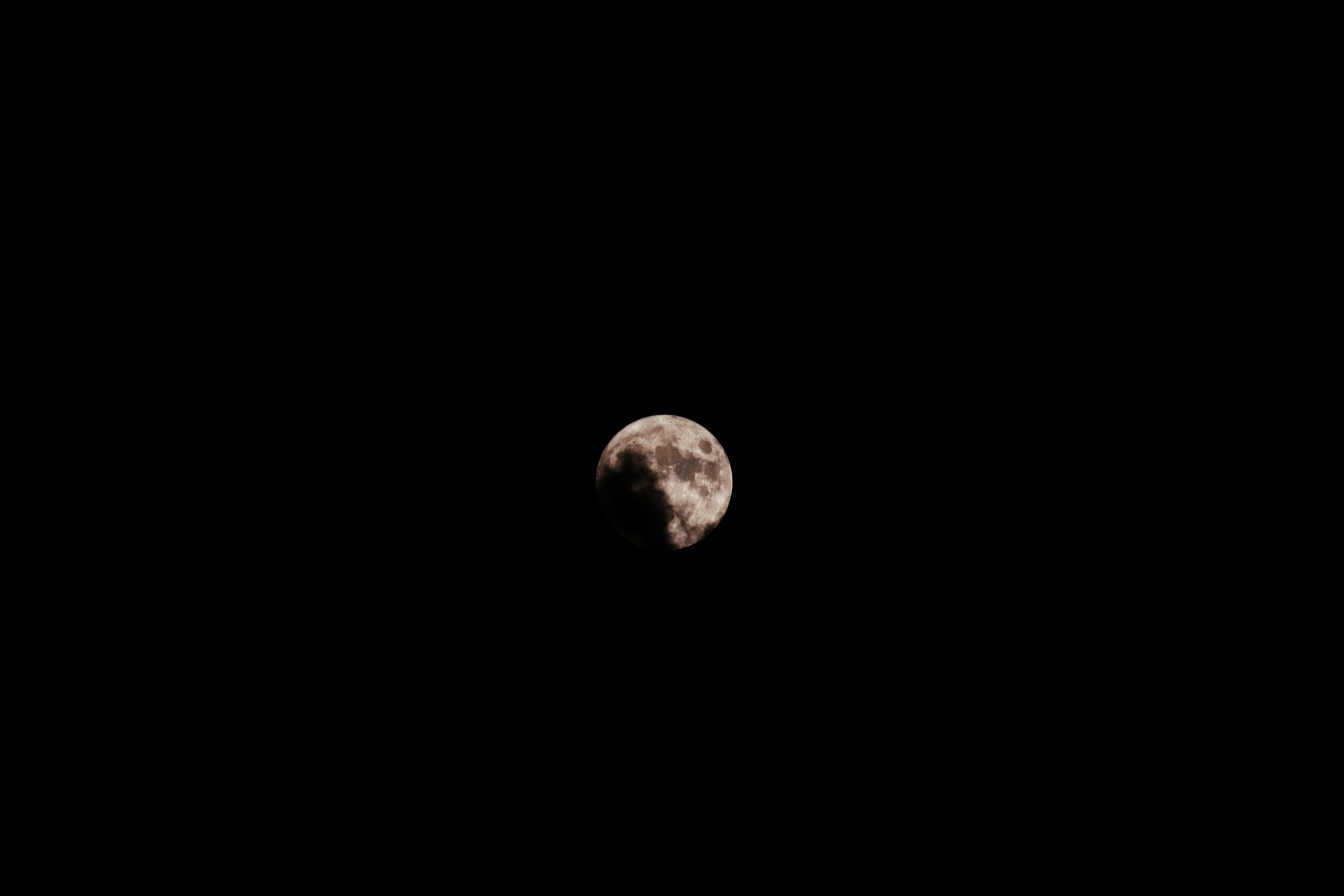 Image of the moon floating against a dark cosmic background featuring bright and dark areas